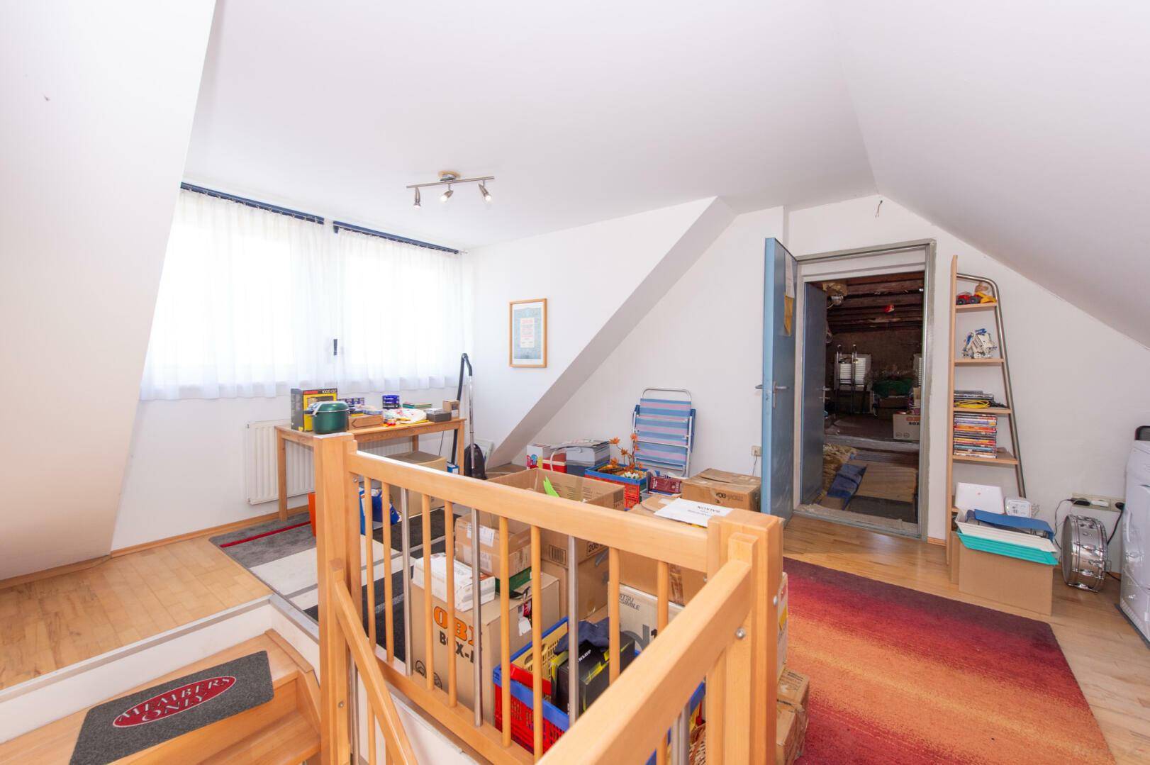 Dachbodenbereich mit Treppenzugang, Schrägen und Fenster.