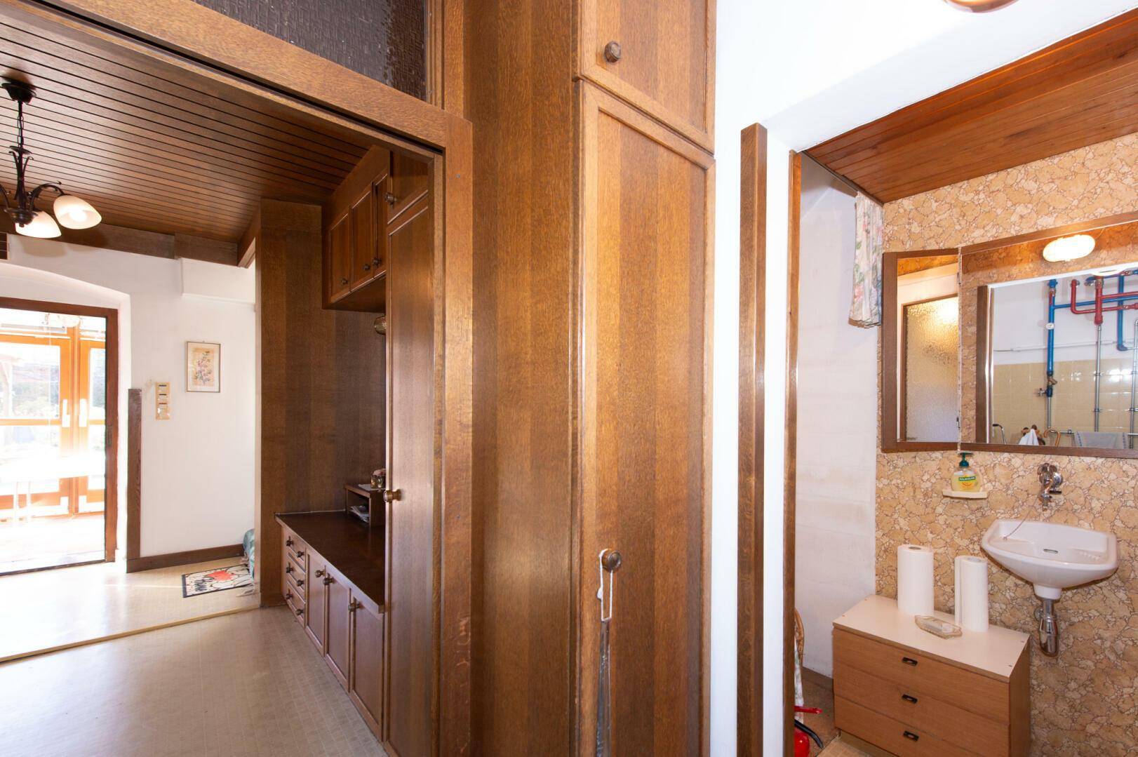 Kellerflur mit Holzvertäfelung und Zugang zu einem WC.