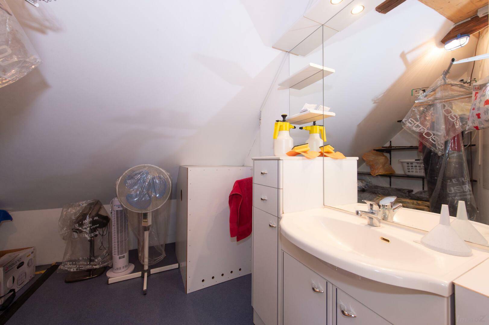 Badezimmer im Dachgeschoss mit Waschbecken, Spiegelschrank und Schrägen.