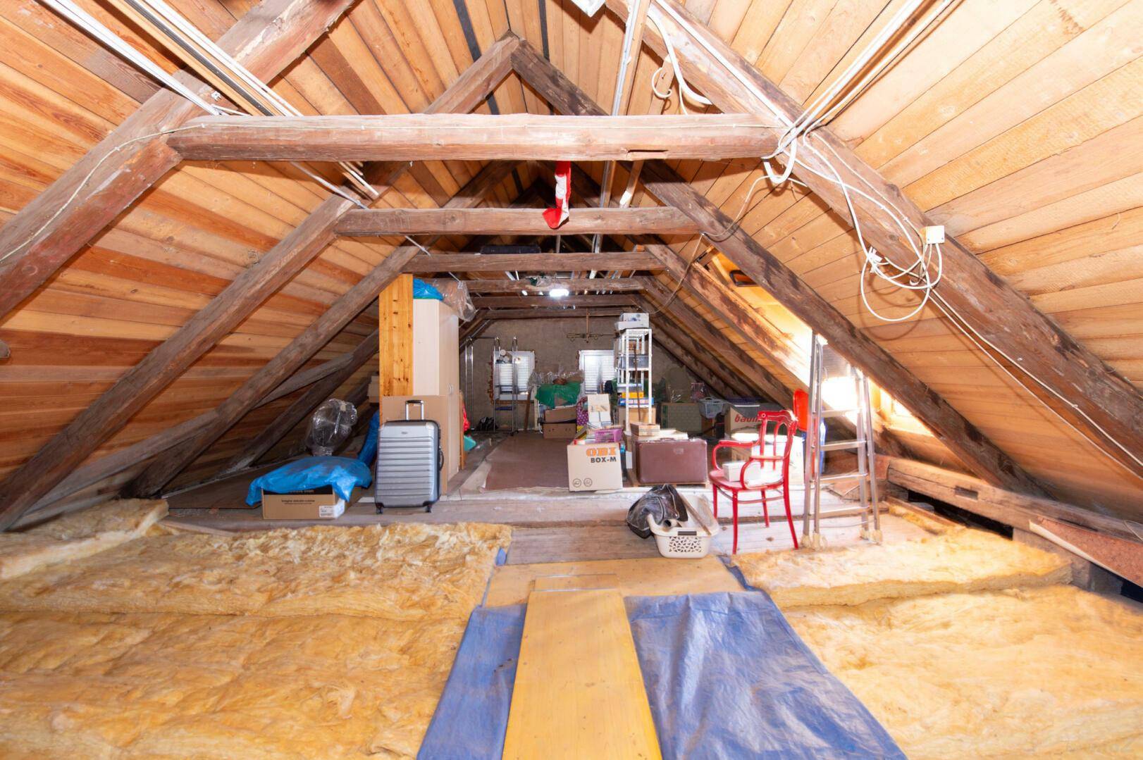 Unfertiger Dachboden mit sichtbarer Holzkonstruktion und Isolierung.