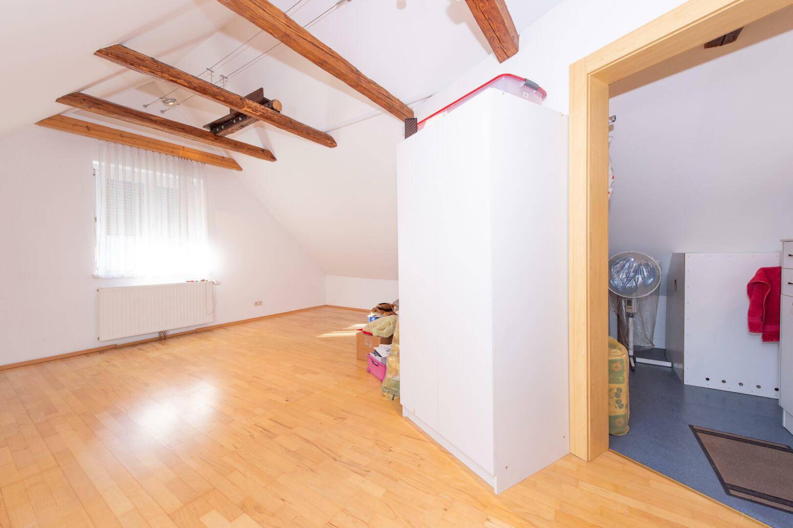Dachboden mit Holzboden, Schrägen und Zugang zu einem weiteren Bereich.