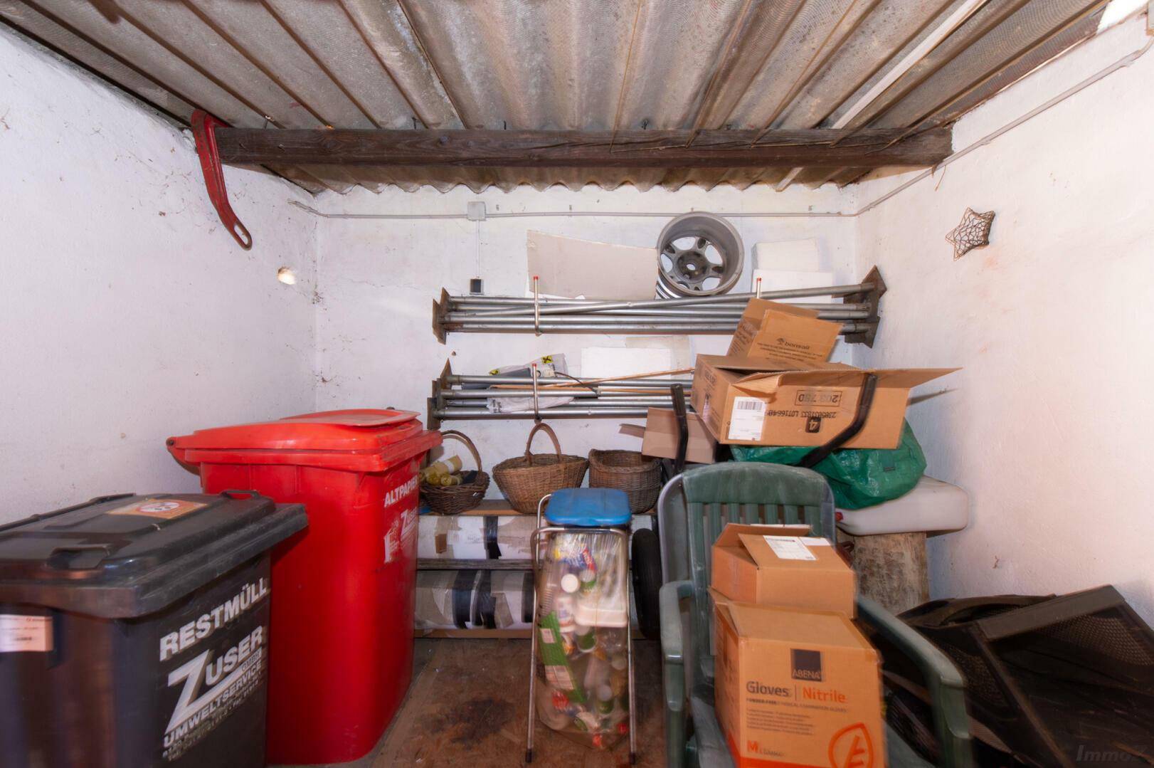Kellerraum mit Mülltonnen und Regalen für Lagerung.