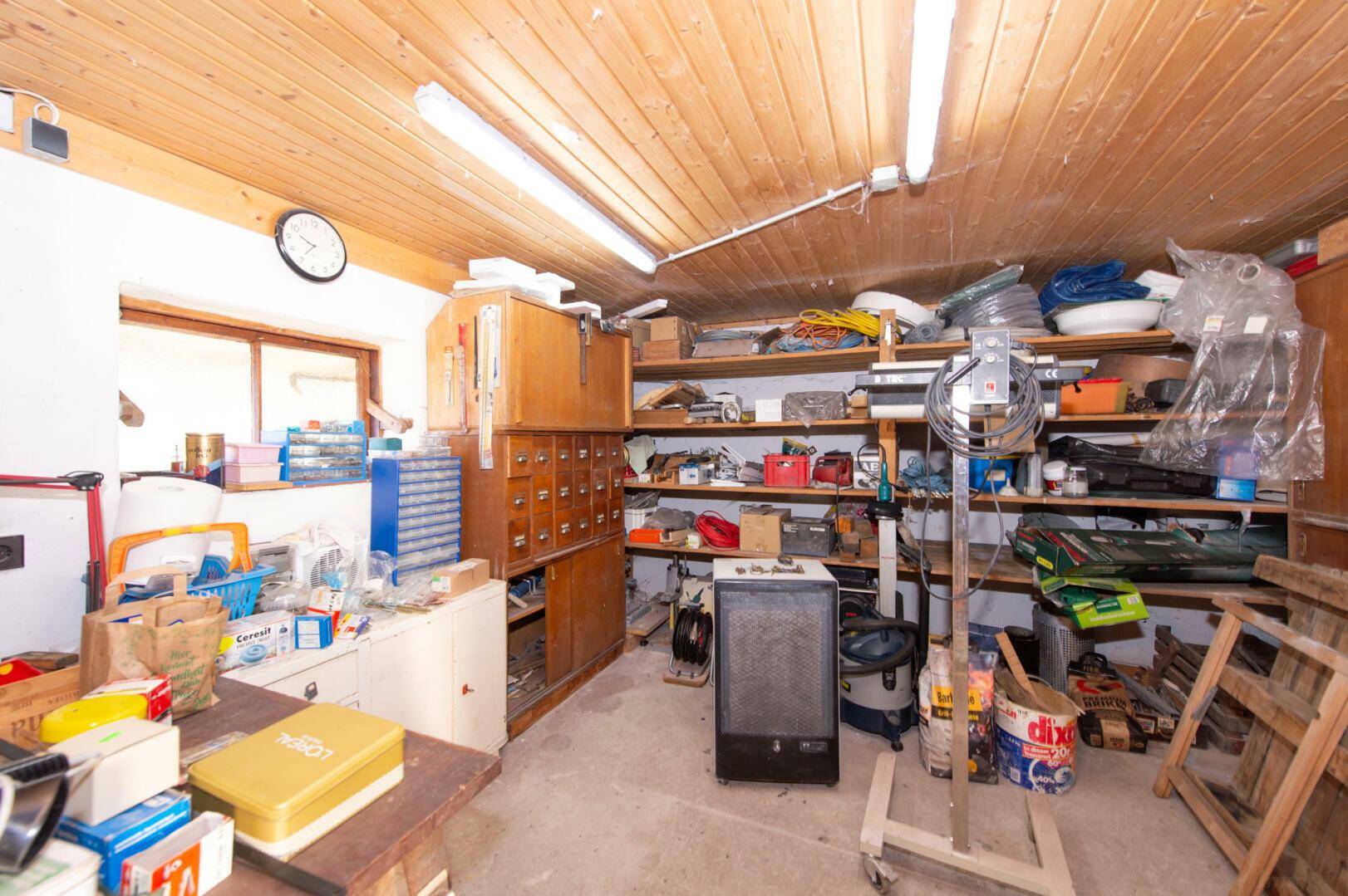 Werkstatt mit Regalen, Werkzeugen und Holzdecke.