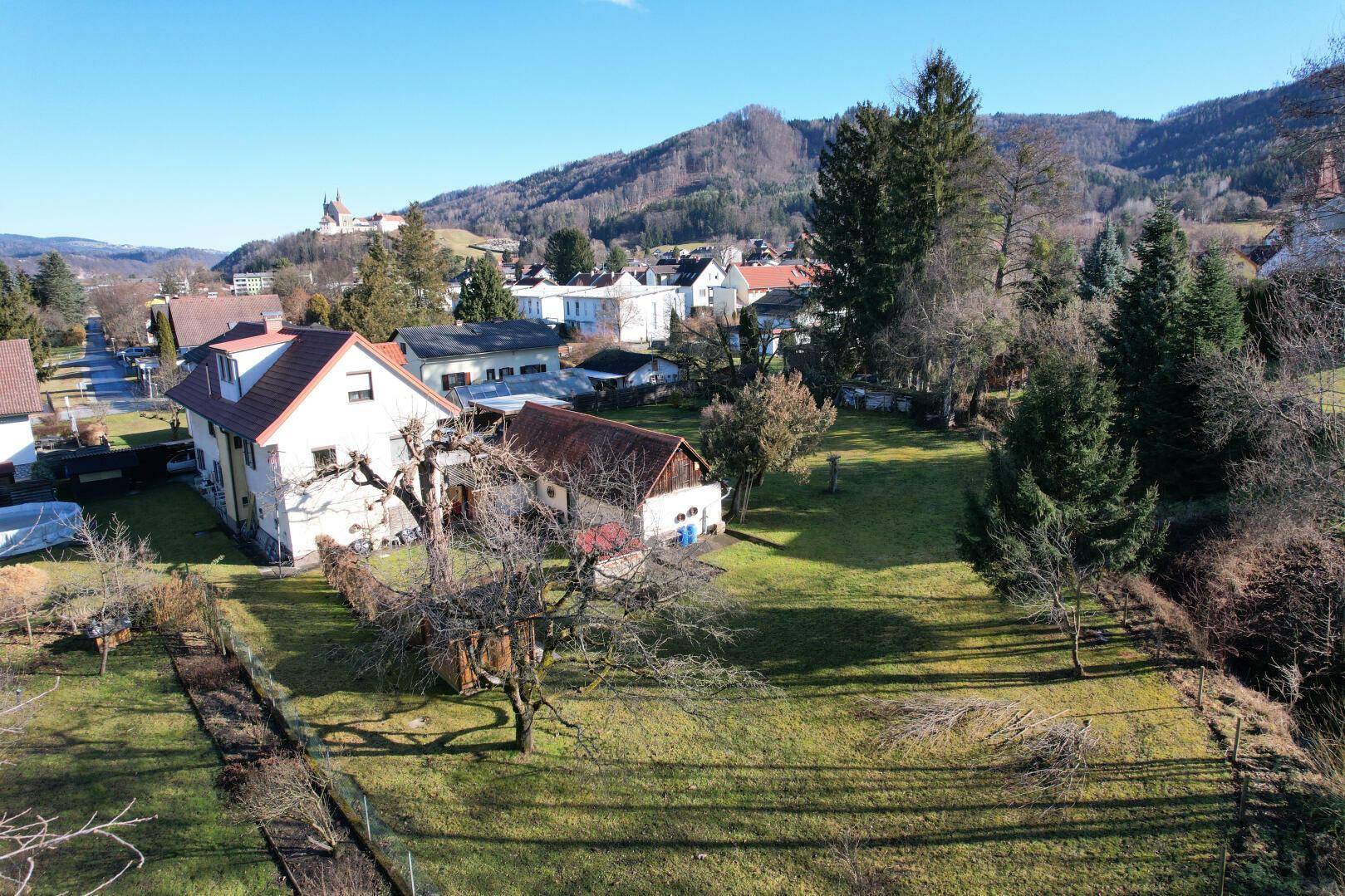 Weitläufige Gartenanlage mit Baumbestand und Blick auf die umliegende Landschaft und Berge.
