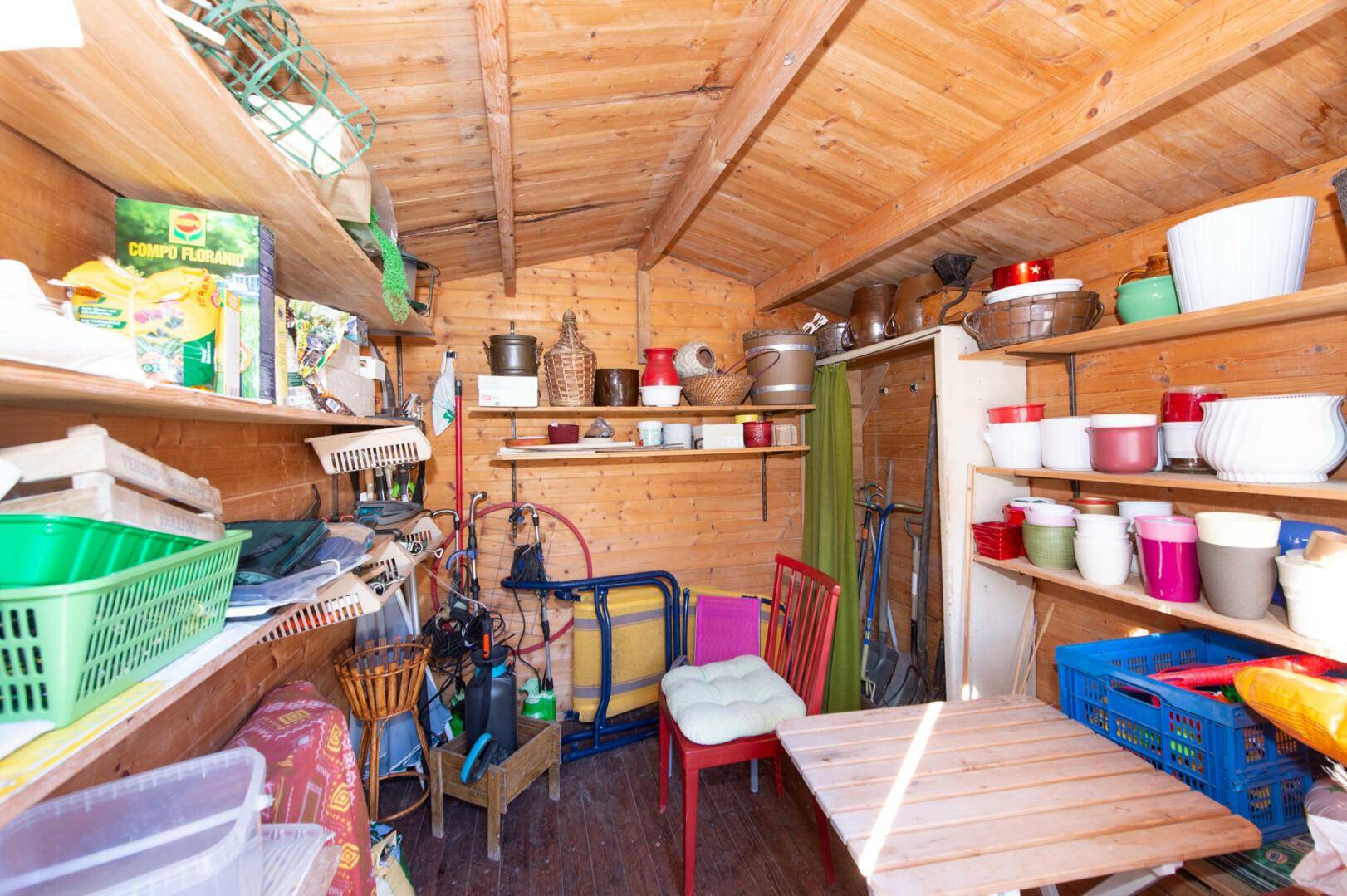 Innenraum des Gartenhauses mit Regalen und Gartengeräten.