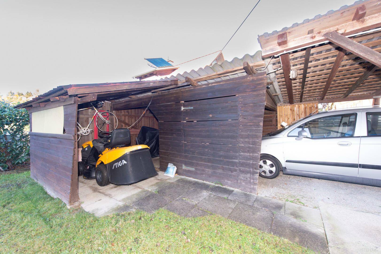 Carport mit angrenzendem Abstellbereich für Gartengeräte.