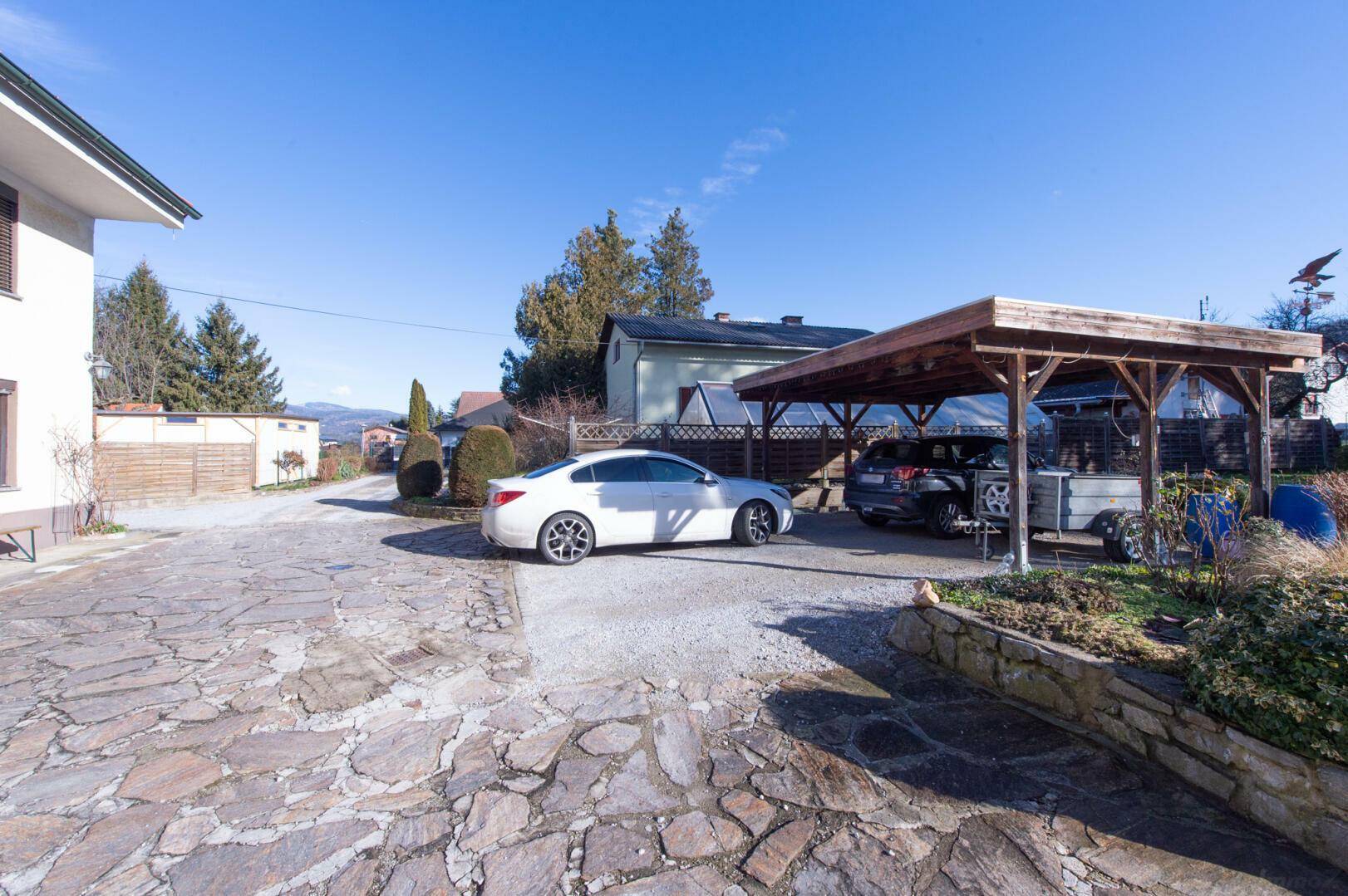 Gepflasterte Einfahrt mit Parkplätzen und einem Carport.
