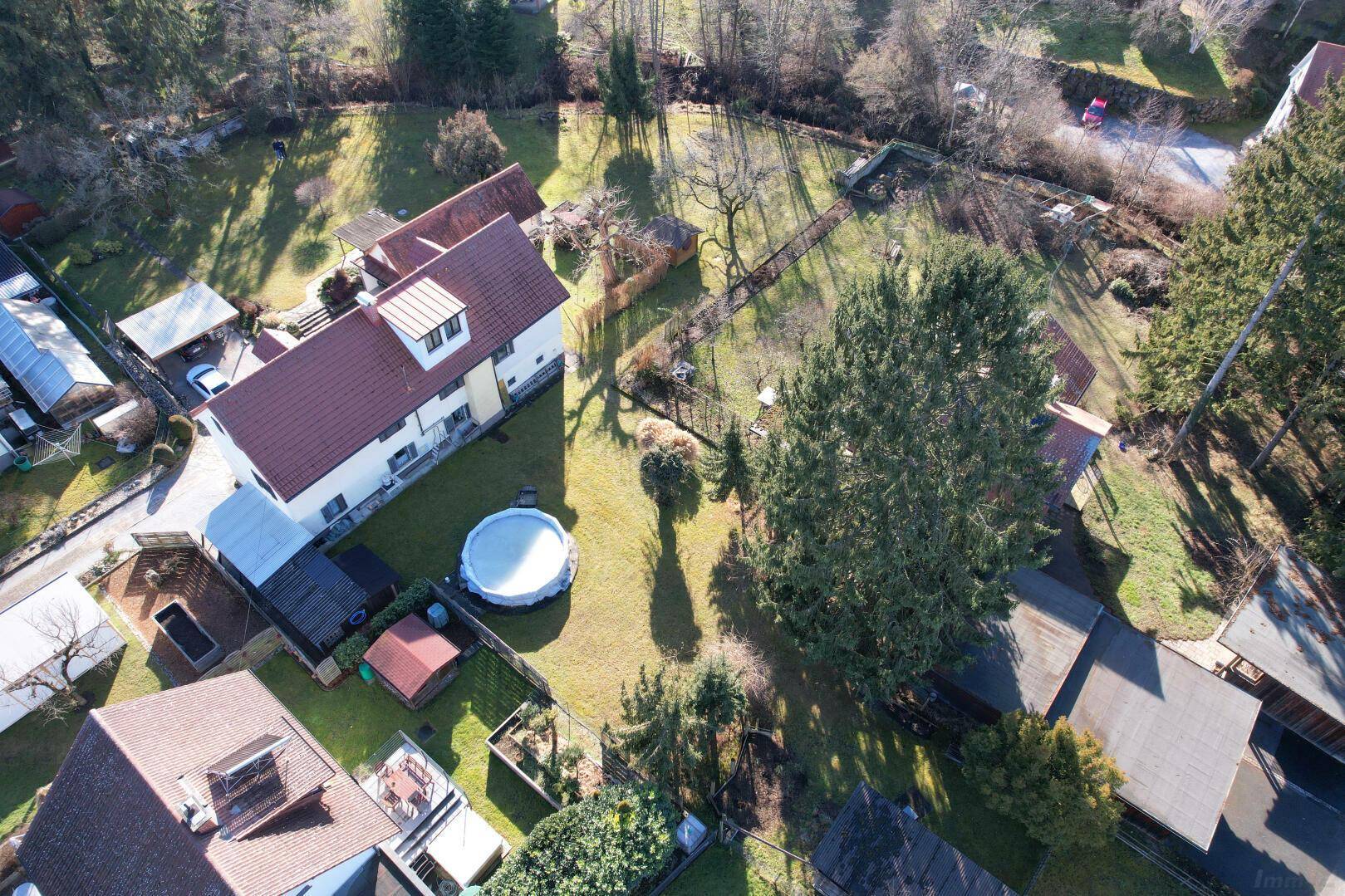 Draufsicht des Grundstücks mit Haus, großem Garten, Bäumen und einem Aufstellpool.