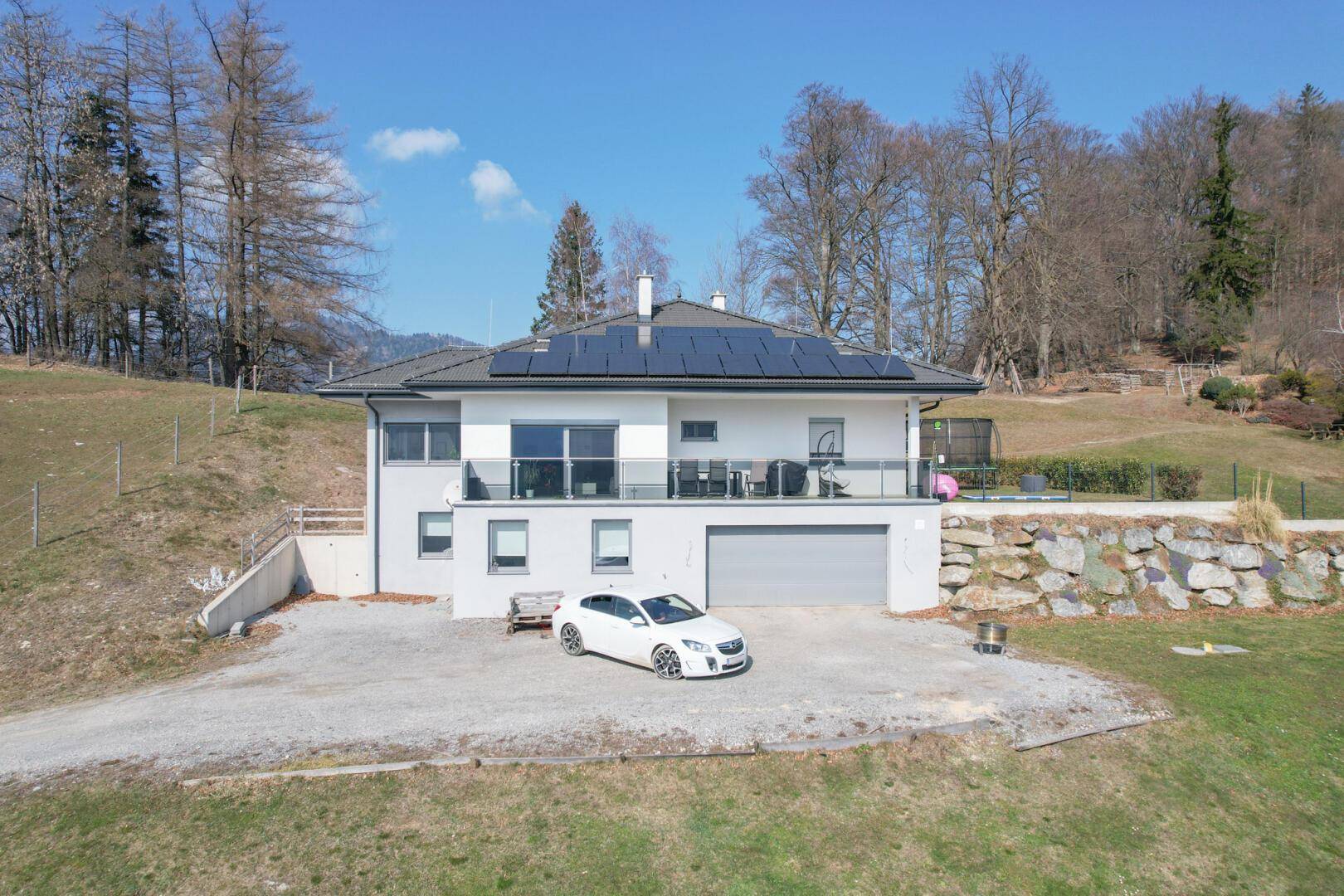 Modernes Einfamilienhaus mit Photovoltaikanlage auf dem Dach und Garage im Untergeschoss.