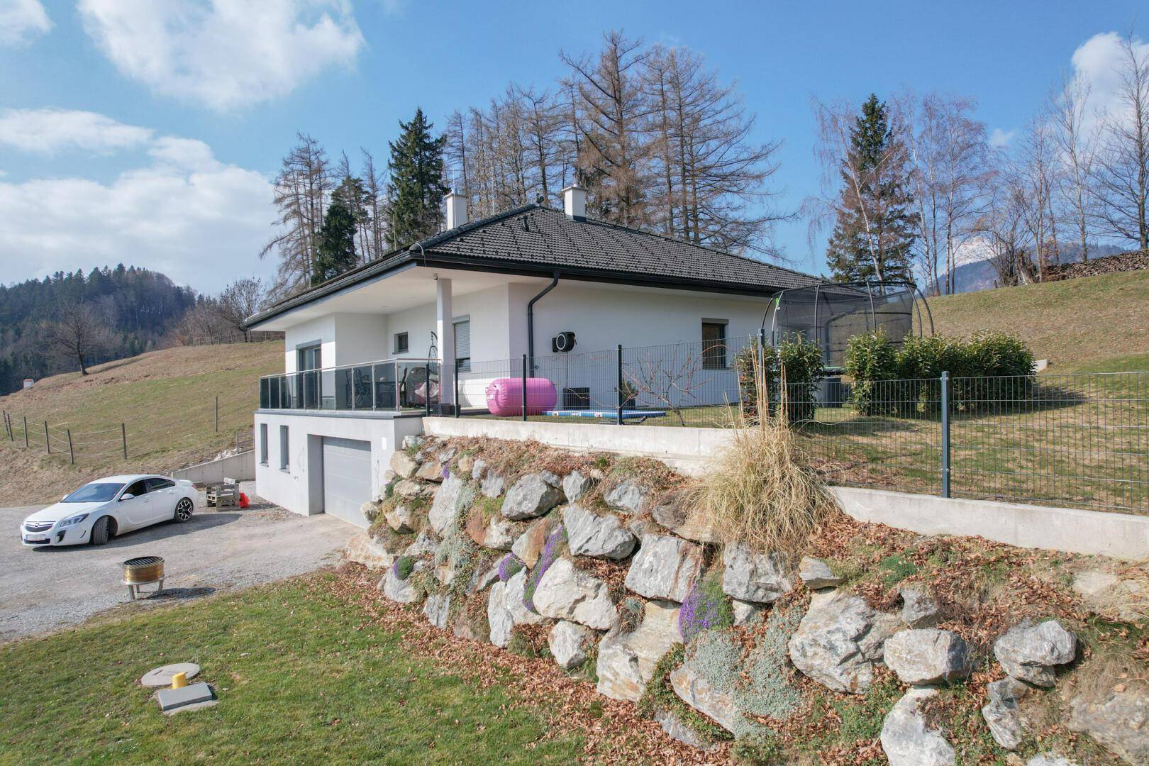 Ansicht des modernen Hauses mit Felsmauer und Gartenbereich in sonniger Lage.