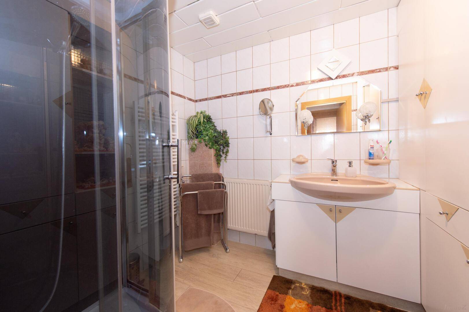 Traditionelles Badezimmer mit Dusche, Waschbecken und Fliesen in hellem Design.