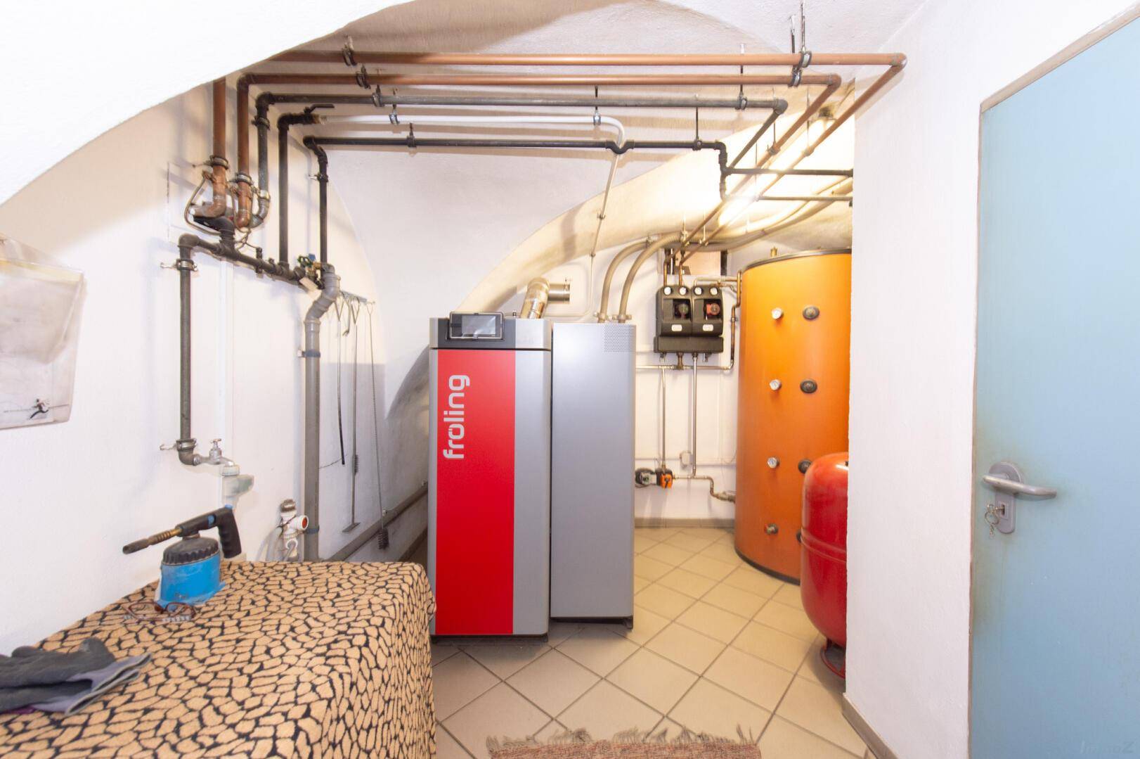 Heizungsraum mit modernem Heizkessel und Warmwasserspeicher im Altbau.