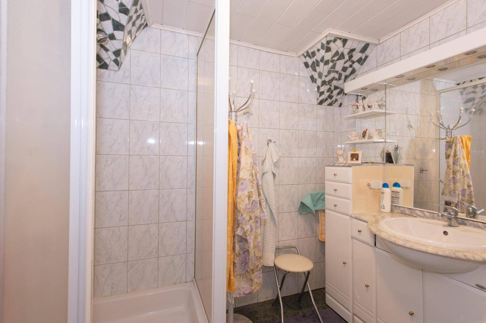 Traditionelles Badezimmer mit Dusche, Waschbecken und Fliesen in hellem Design.