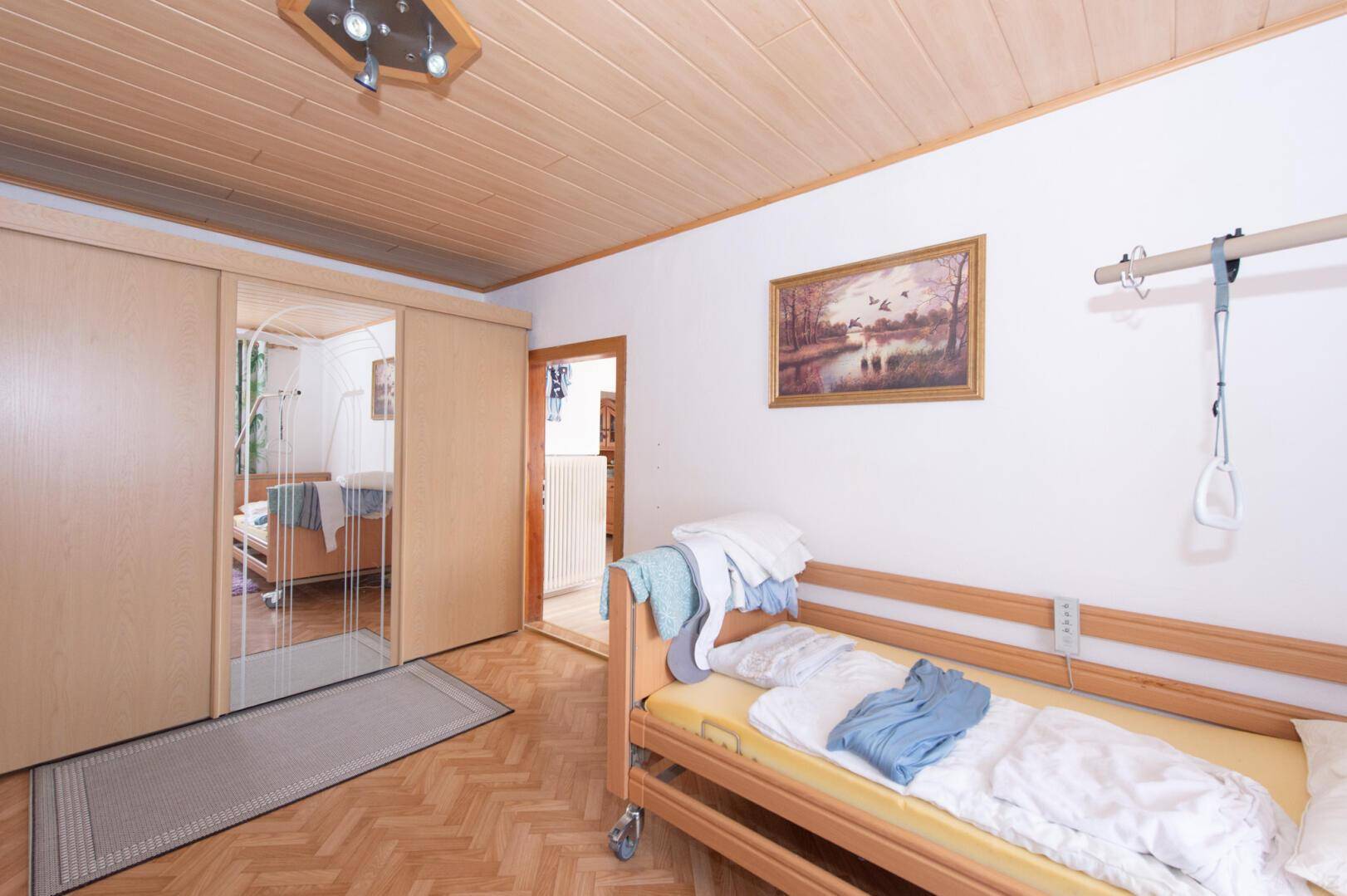 Traditionelles Schlafzimmer mit Holzboden, Holzdecke und Schiebetürenschrank.