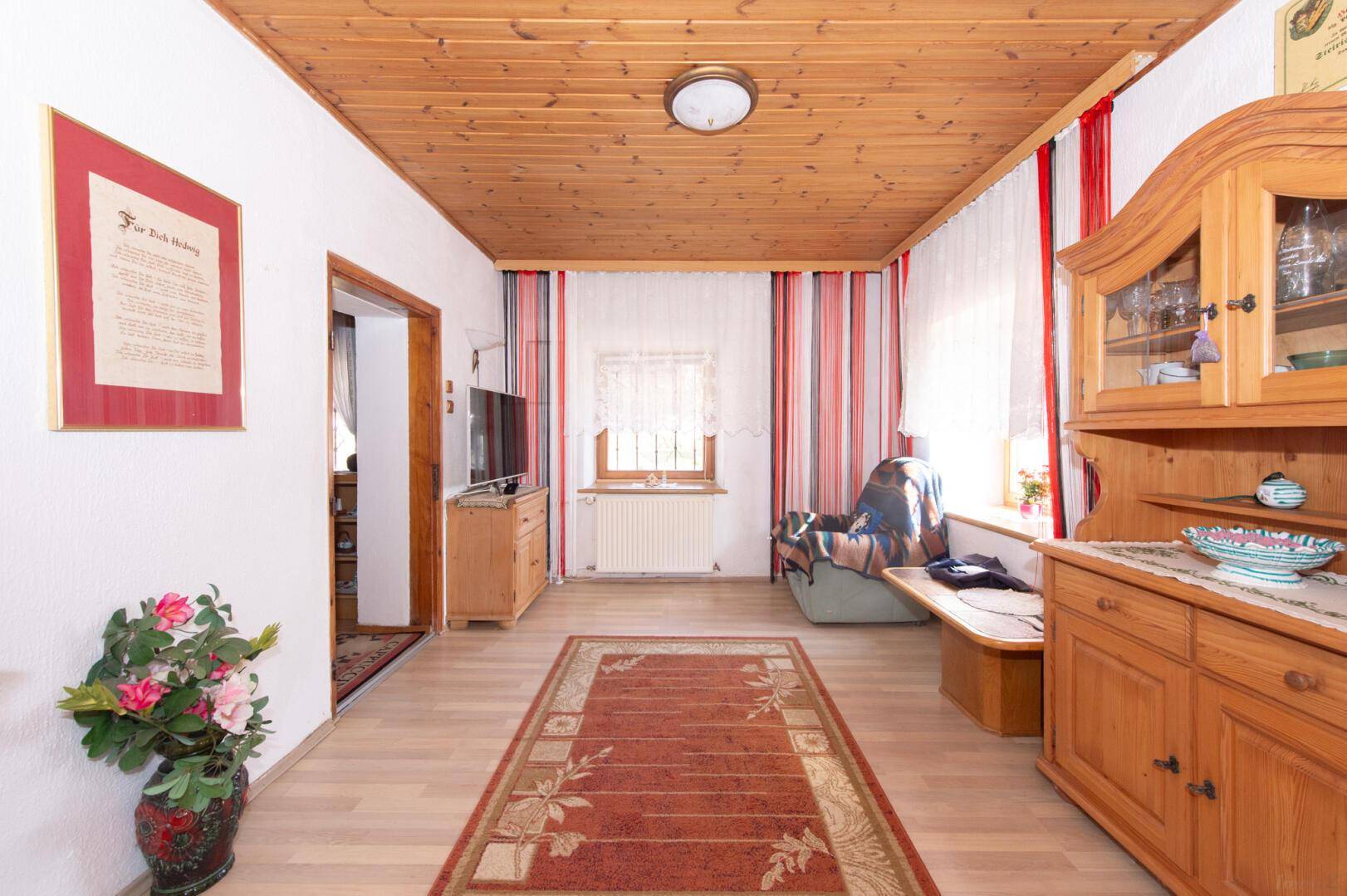 Gemütliches Wohnzimmer mit Holzboden, Holzmöbeln und traditioneller Einrichtung.