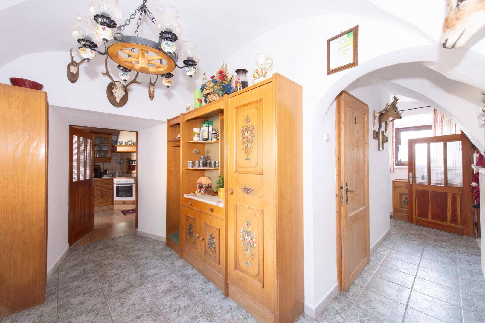 Traditioneller Eingangsbereich mit Gewölbedecke, Fliesenboden und rustikalen Holzmöbeln.