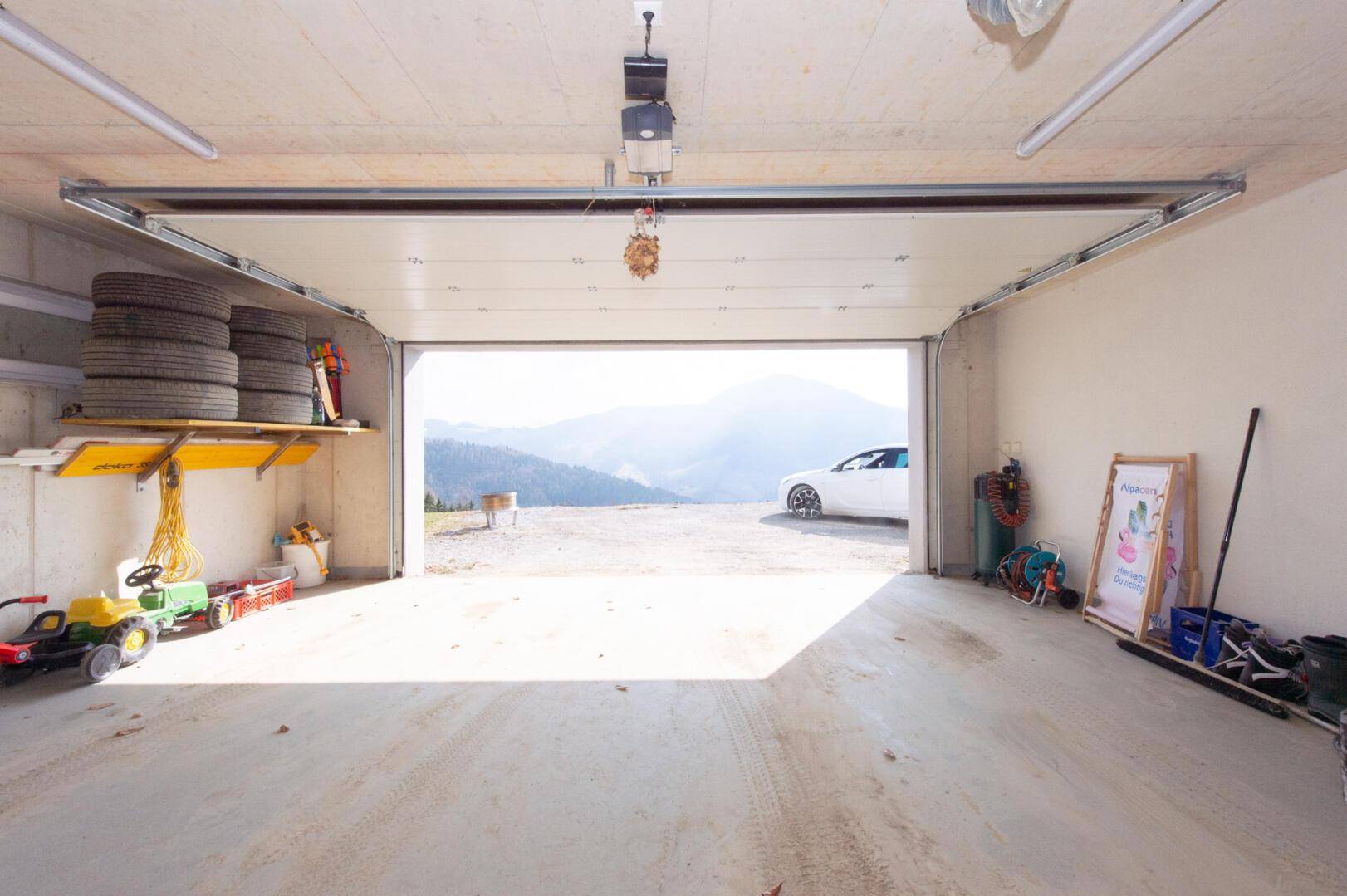 Geräumige Garage mit automatischem Tor und Blick auf die Berglandschaft.