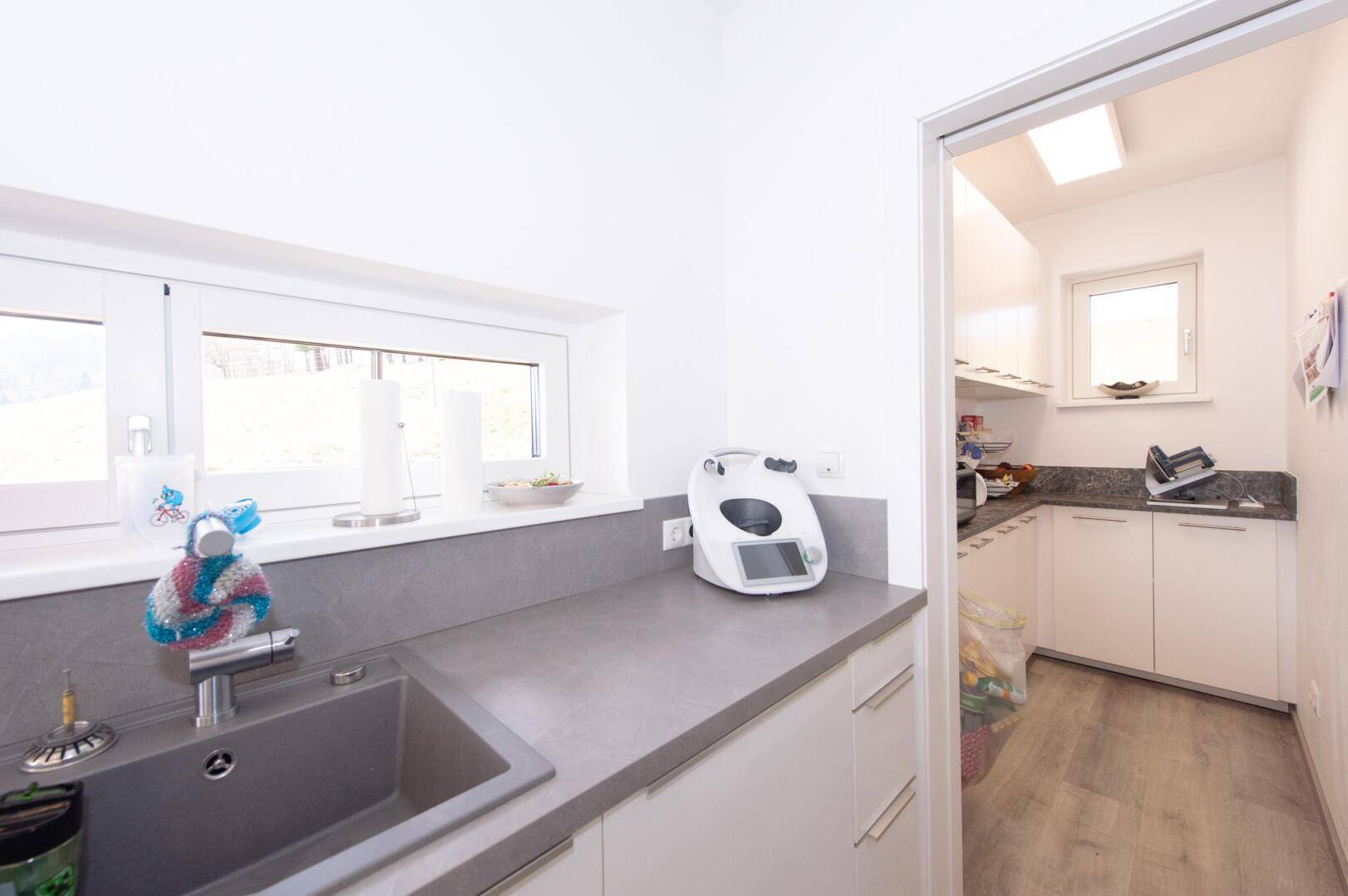 Praktische Speisekammer mit Fenster, Regalen und zusätzlichem Stauraum neben der Küche.