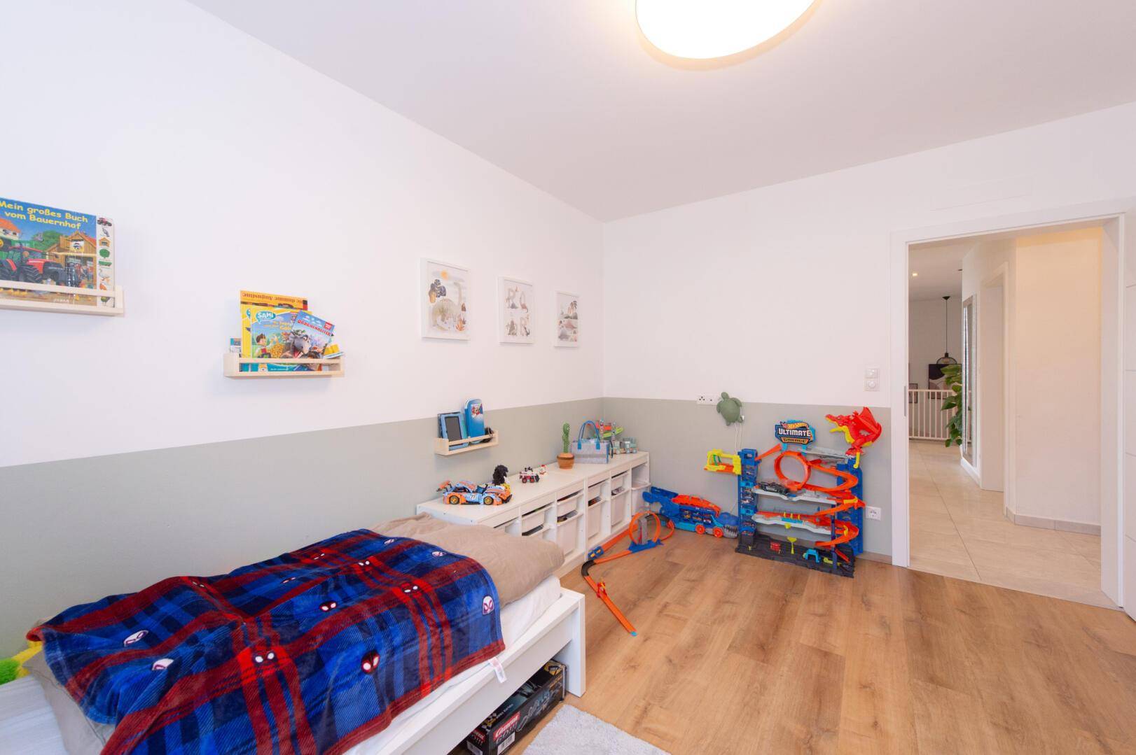 Helles Kinderzimmer mit Holzboden, Spielbereich und Blick in den Flur.
