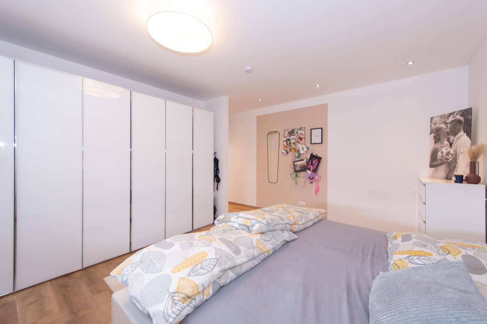 Geräumiges Schlafzimmer mit großen Einbauschränken, Holzboden und moderner Einrichtung.