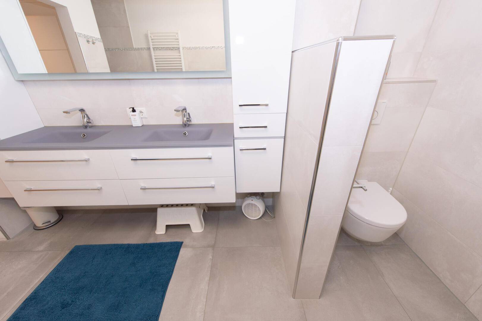 Modernes Badezimmer mit Badewanne, Doppelwaschbecken und Wand-WC.