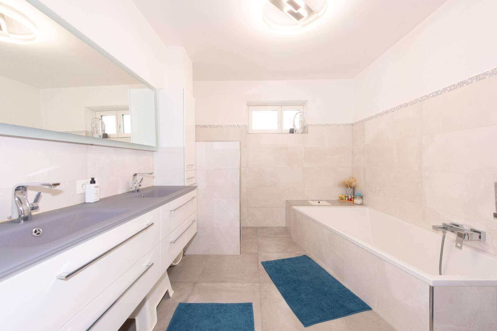 Geräumiges Badezimmer mit Badewanne, Doppelwaschbecken und modernen Fliesen.