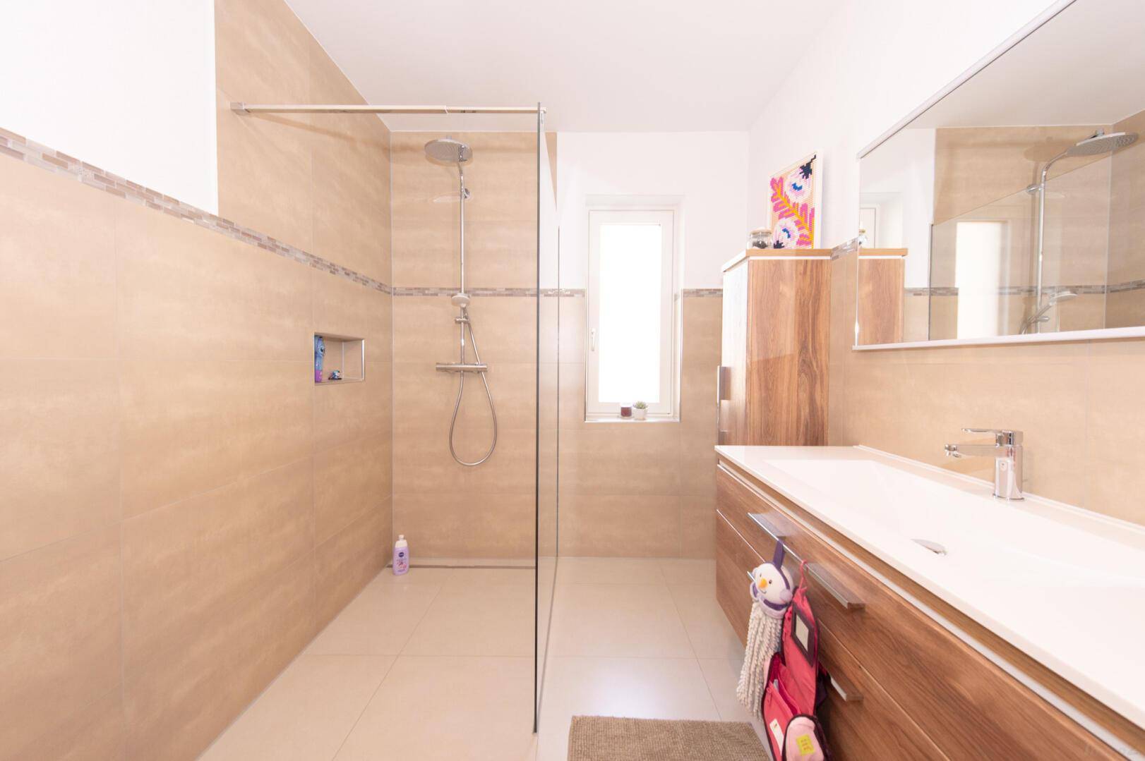 Modernes Badezimmer mit begehbarer Dusche, Doppelwaschbecken und Holzunterschränken.