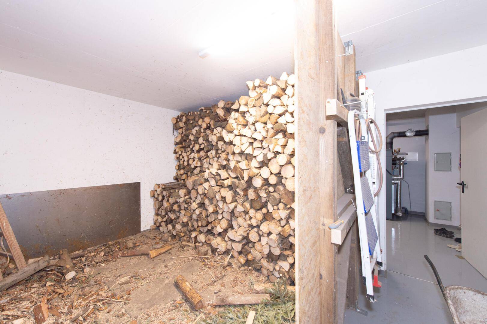Lagerraum für Brennholz mit großem Holzstapel und Zugang zum Heizungsraum.