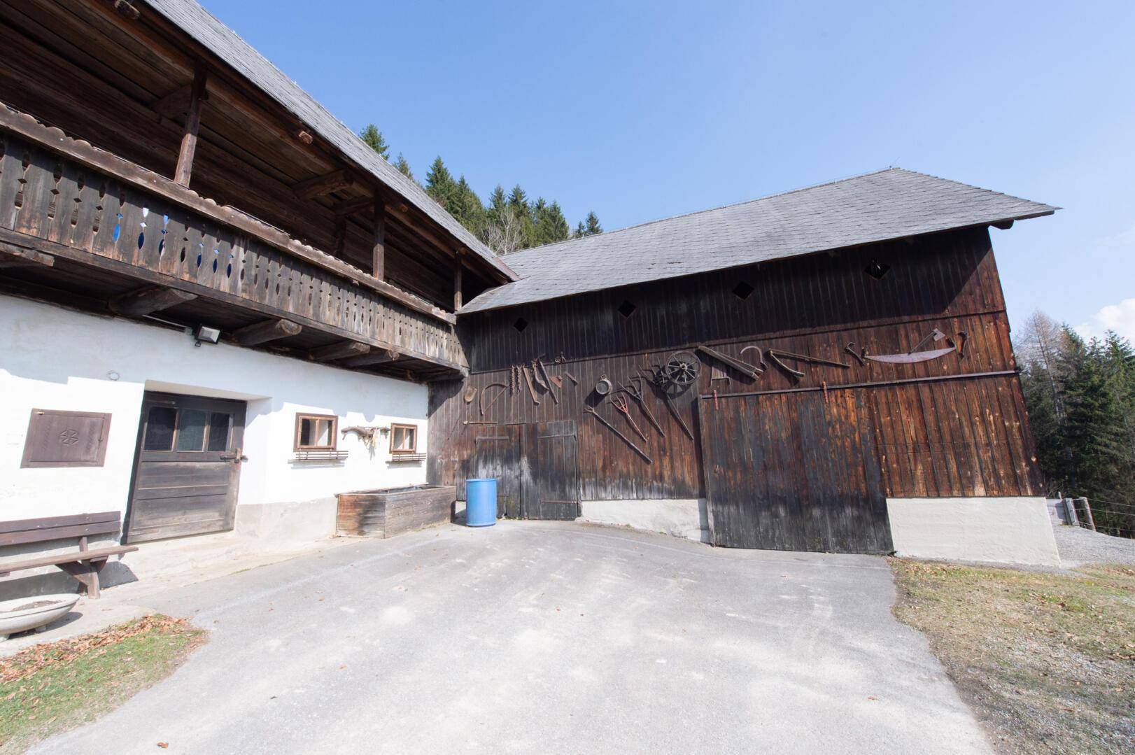 Rustikale Scheune mit Holzwänden und traditionellen landwirtschaftlichen Geräten an der Fassade.