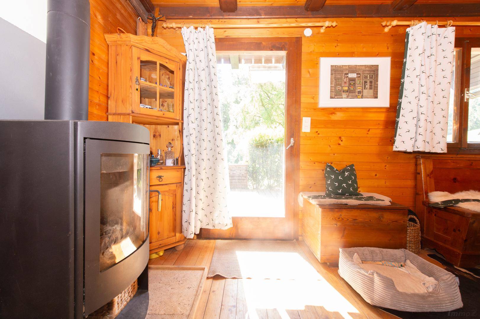 Gemütlicher Wohnbereich mit Kaminofen, Holzboden und direktem Zugang zum Außenbereich.