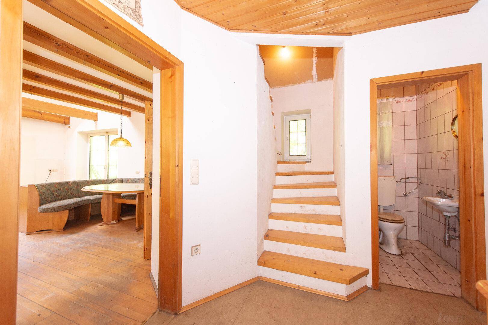 Heller Flur mit Holztreppe und Zugang zu einem Essbereich und einem Badezimmer.