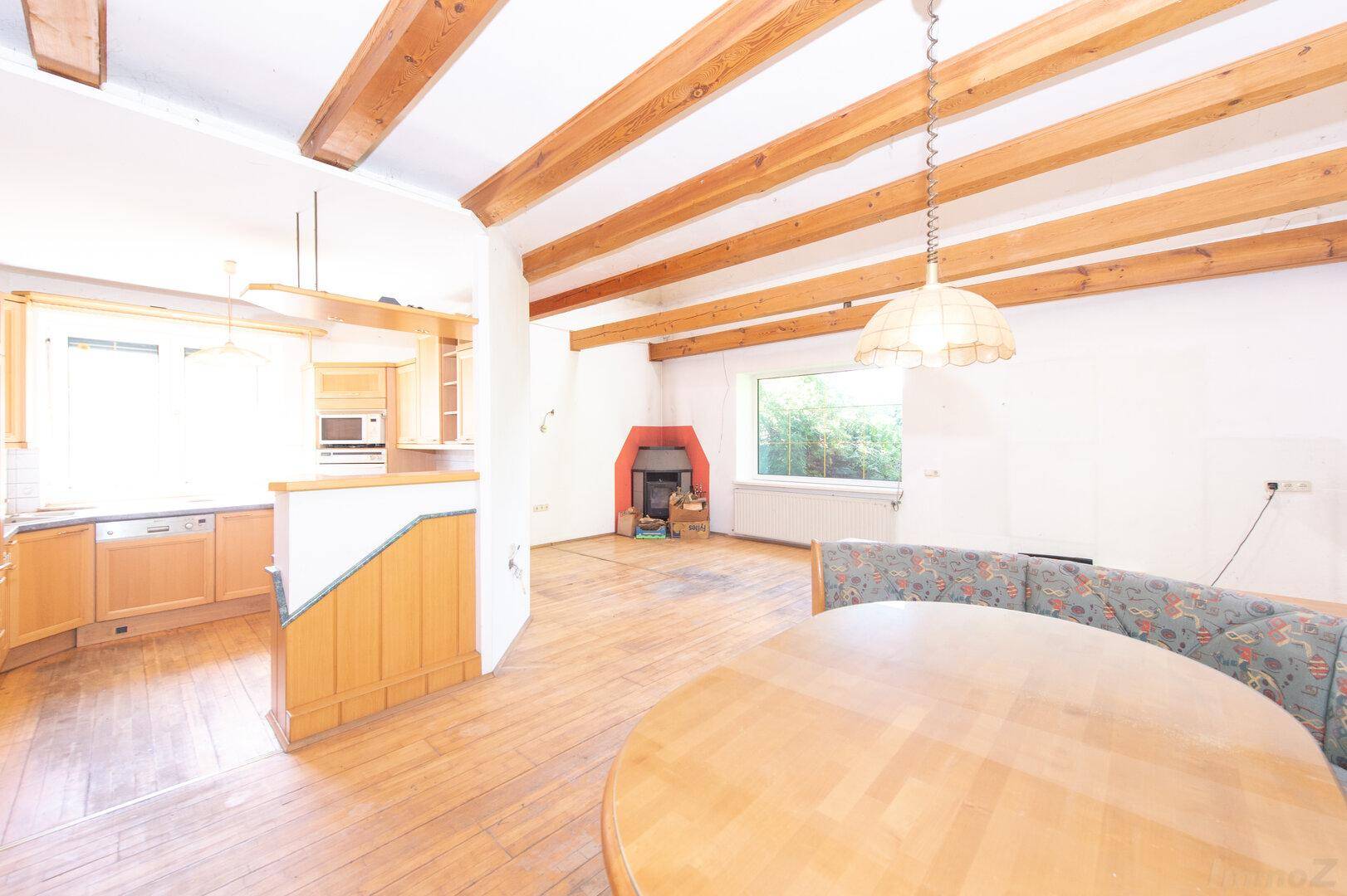 Offener Wohn- und Essbereich mit Holzbalkendecke, Kamin und Holzboden.