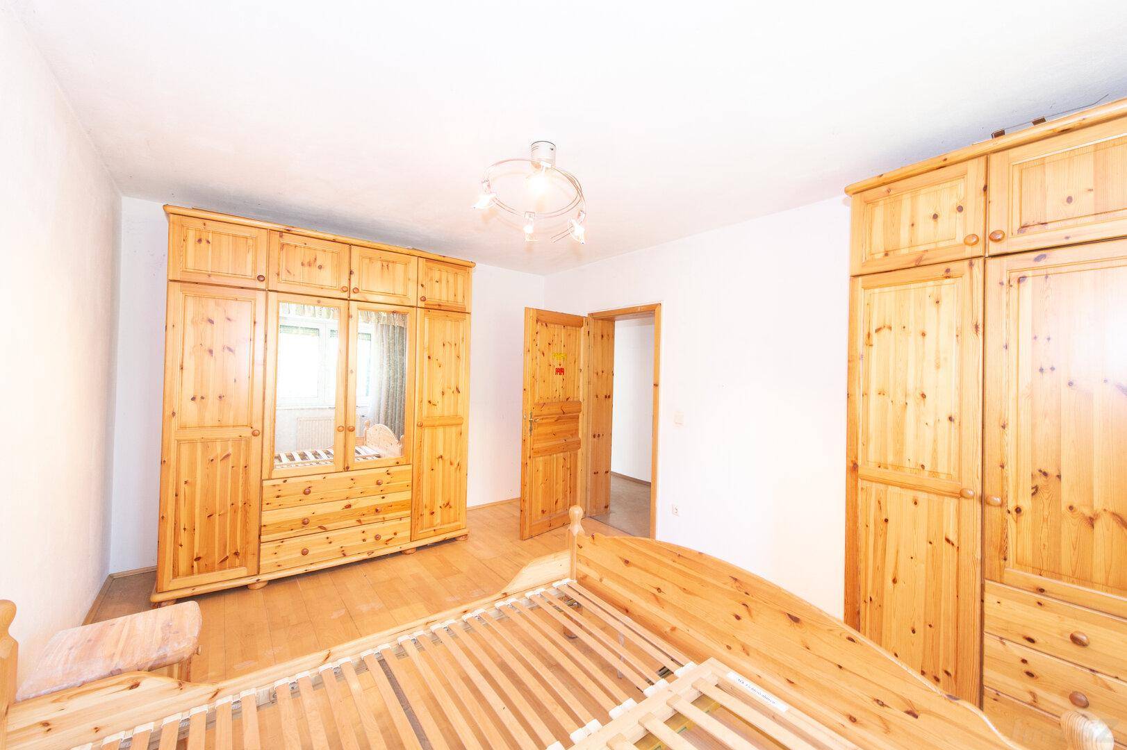 Schlafzimmer mit Holzbett, großen Holzschränken und Holztür.