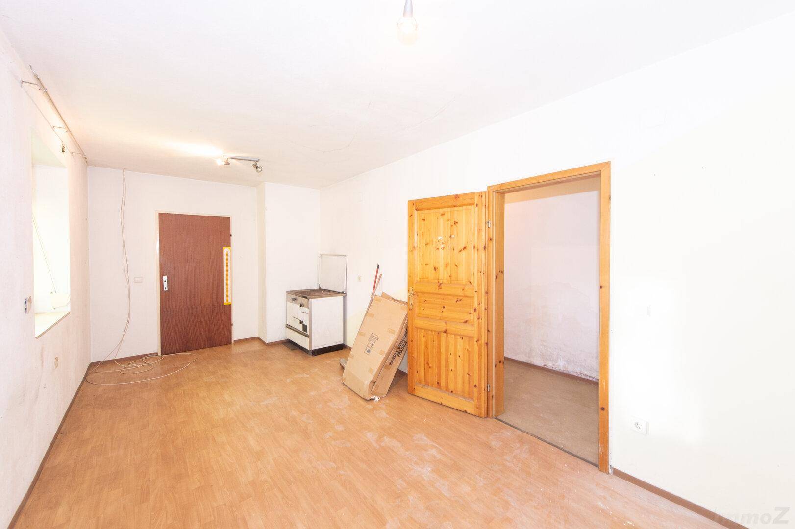 Leerer Raum mit Holzboden, Fenster und Heizkörper, ideal für individuelle Einrichtung.