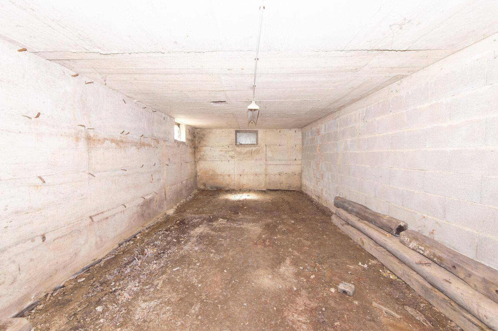 Leerer, unfertiger Kellerraum mit Betonblockwänden und kleinen Fenstern.