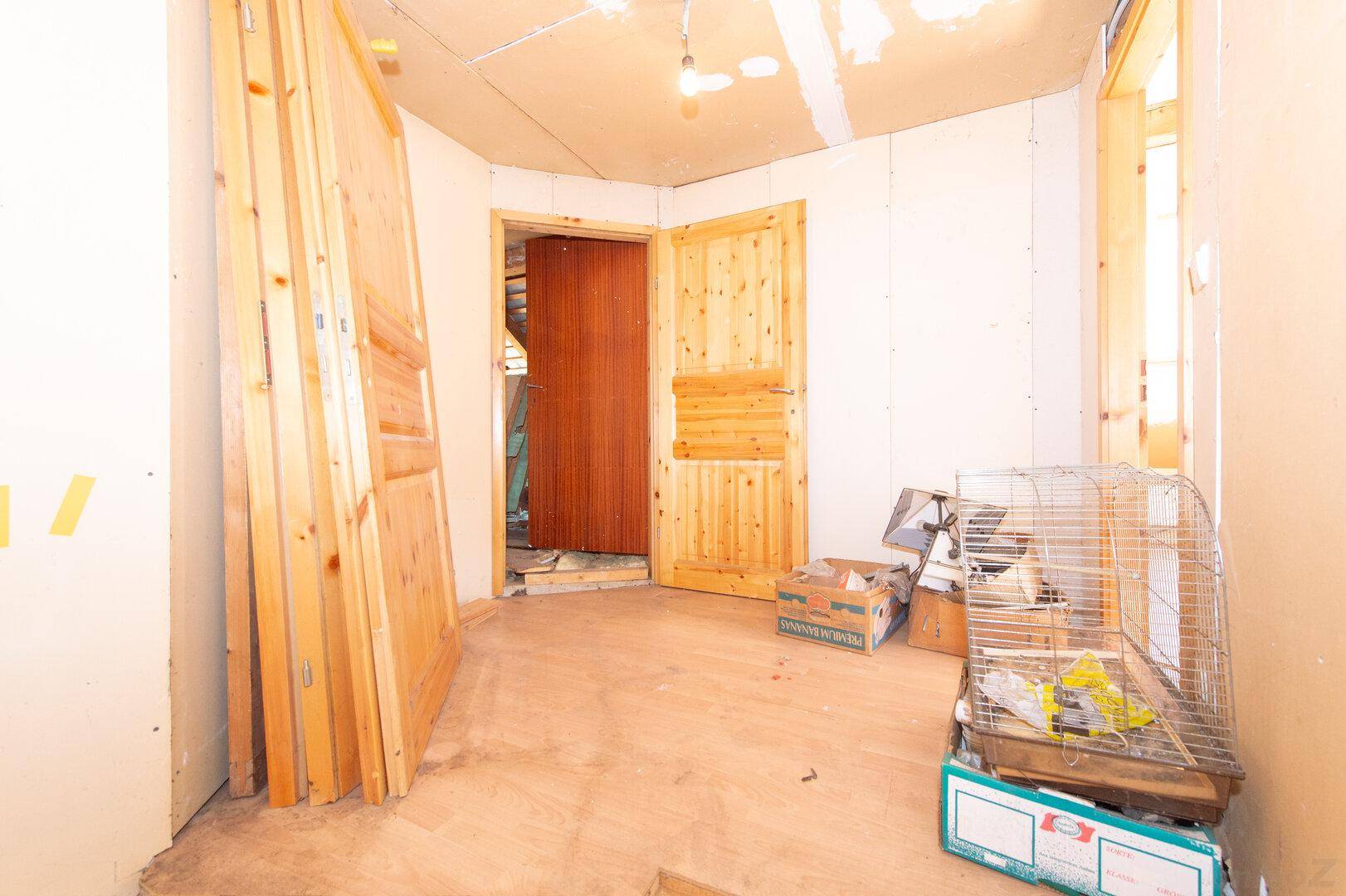 Raum im Umbau mit gestapelten Holztüren und sichtbaren Wandstrukturen.