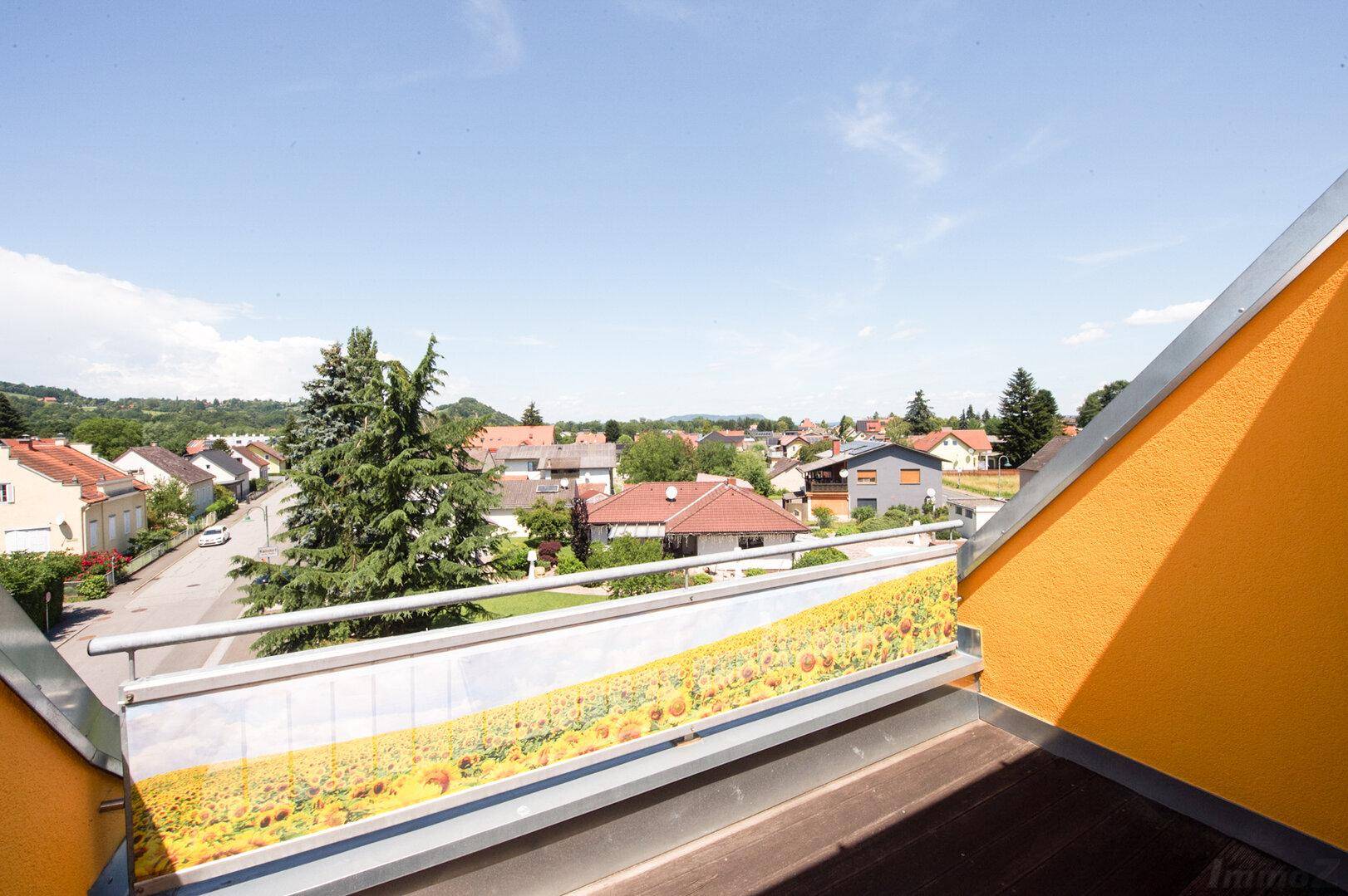 Balkon mit weitem Blick über die umliegende Wohnsiedlung und grüne Landschaft.