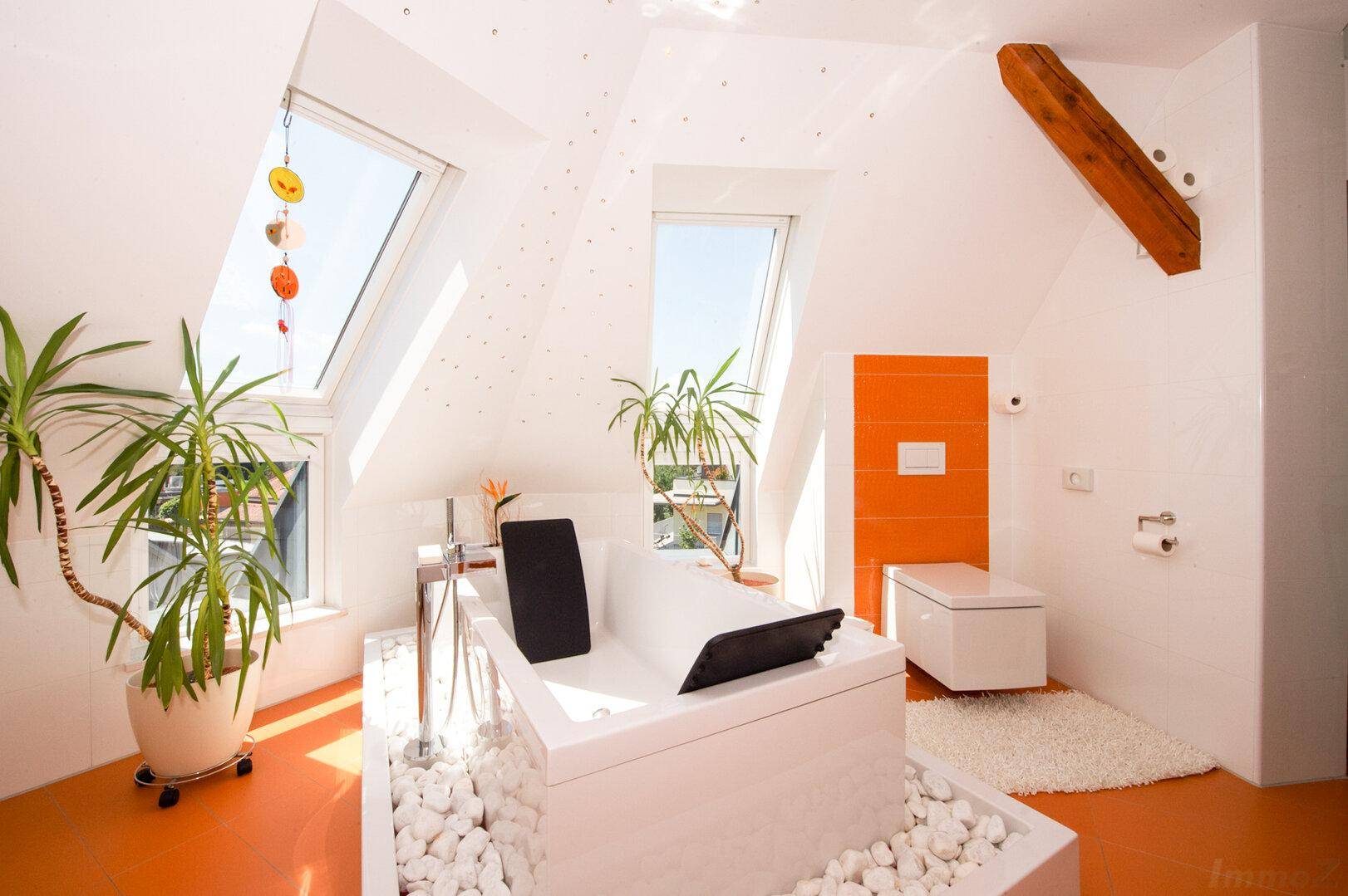 Helles Badezimmer mit Badewanne, Dachfenstern und orangefarbenen Wandfliesen.