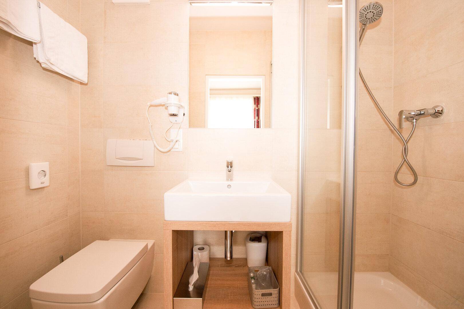 Modernes Badezimmer mit Duschkabine, Waschbecken und wandhängendem WC.