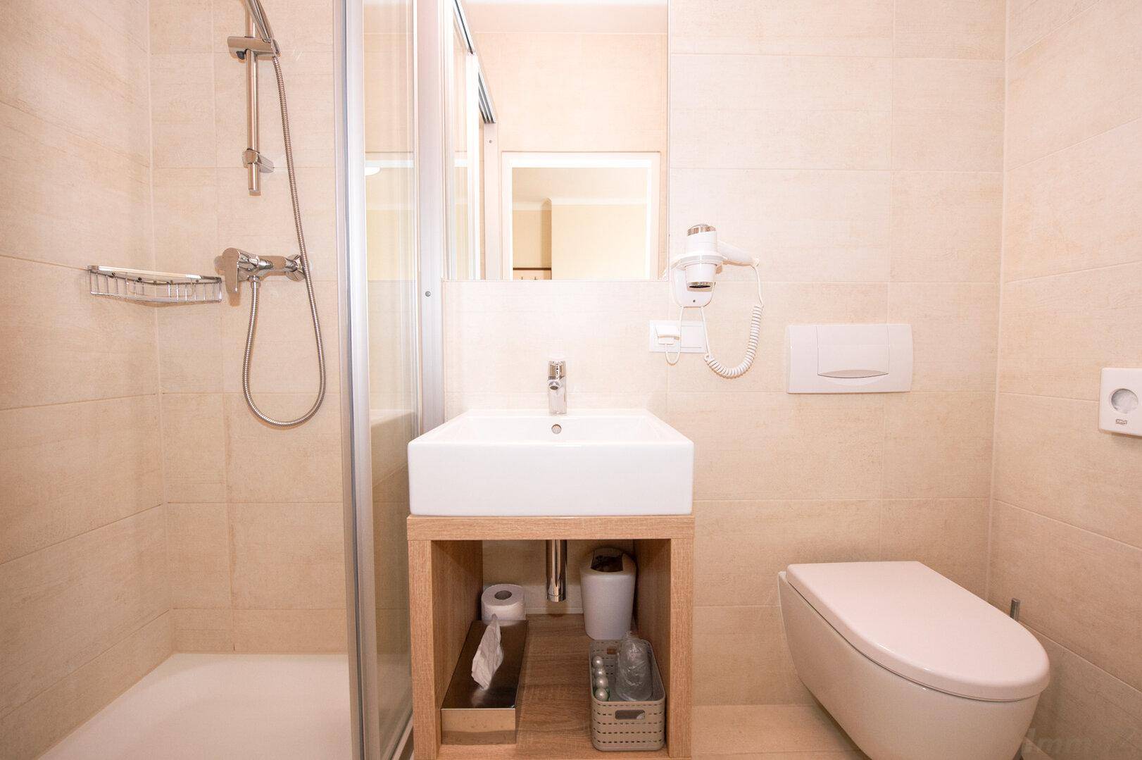 Funktionales Badezimmer mit Duschkabine, modernem Waschbecken und wandhängendem WC.