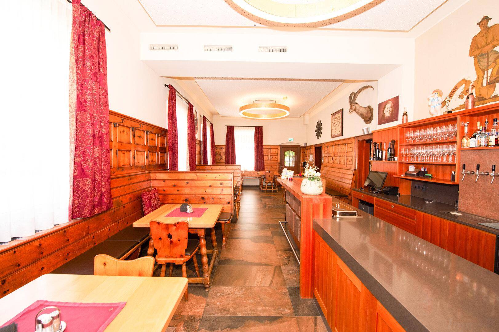 Traditionell eingerichteter Restaurantbereich mit Holztäfelung, Bänken und einer Bar.