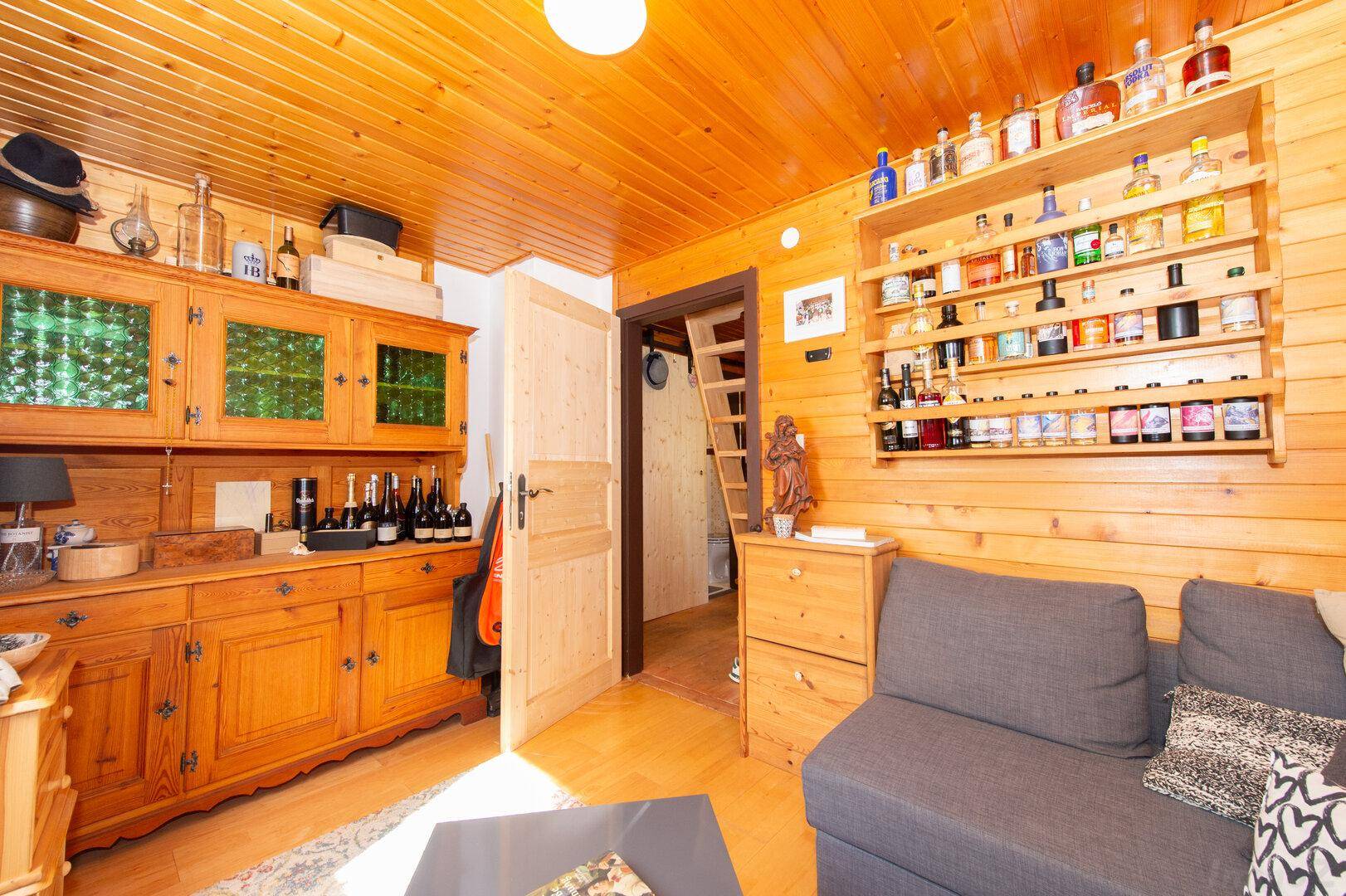 Gemütliches Wohnzimmer mit Holzwänden, Holzdecke und einem rustikalen Sideboard.