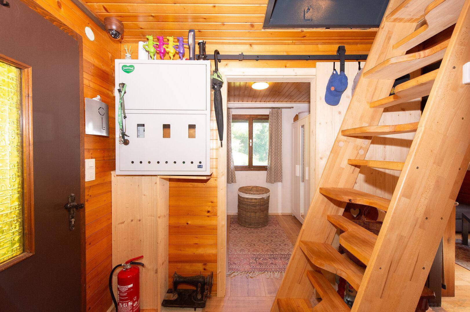 Eingangsbereich mit Holztreppe, Holzwänden und einem Sicherungskasten.