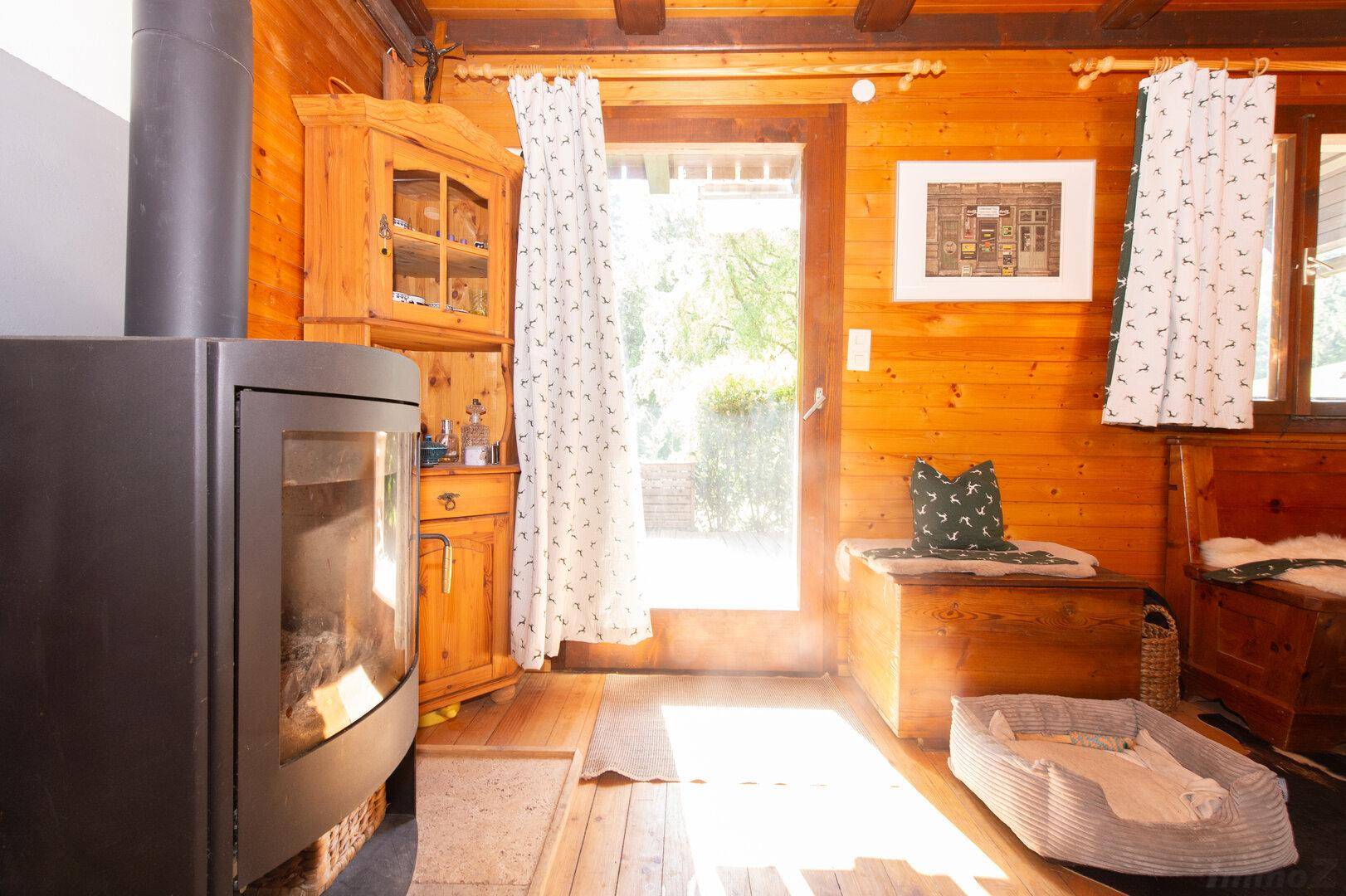 Gemütlicher Wohnbereich mit Kaminofen, Holzboden und großer Terrassentür für viel Licht.