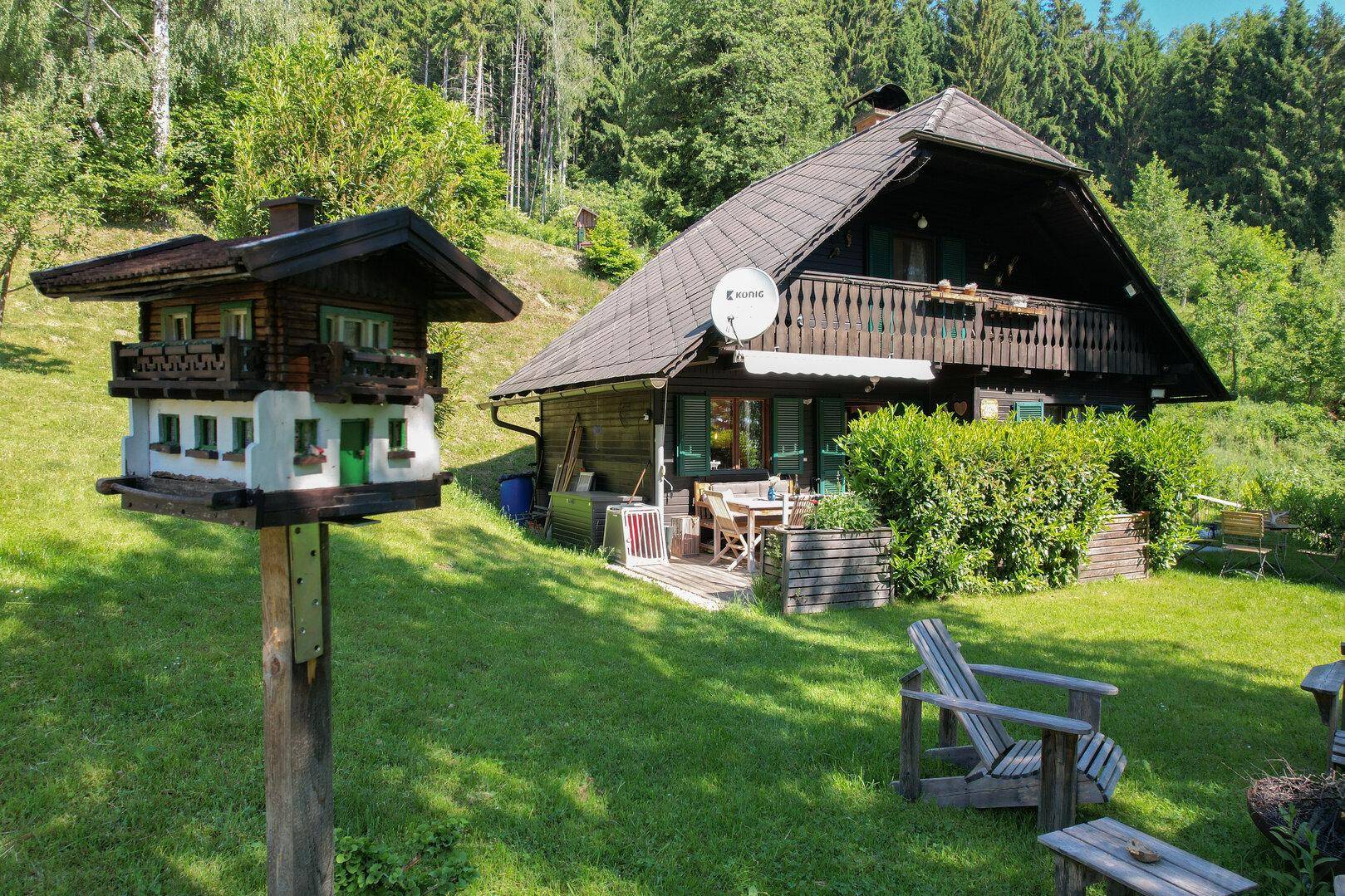 Traditionelles Holzhaus im Chalet-Stil mit möblierter Terrasse und großem Gartenbereich.