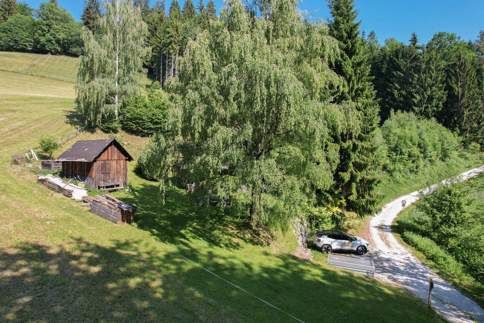 Luftaufnahme des Anwesens mit Wald, Wiesen und einem kleinen Nebengebäude.