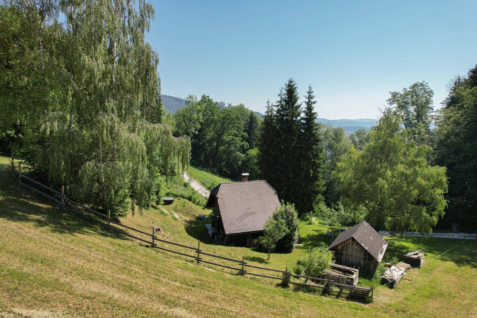 Malerische Landschaftsaufnahme des Anwesens mit Haus, Scheune und weitem Bergblick.