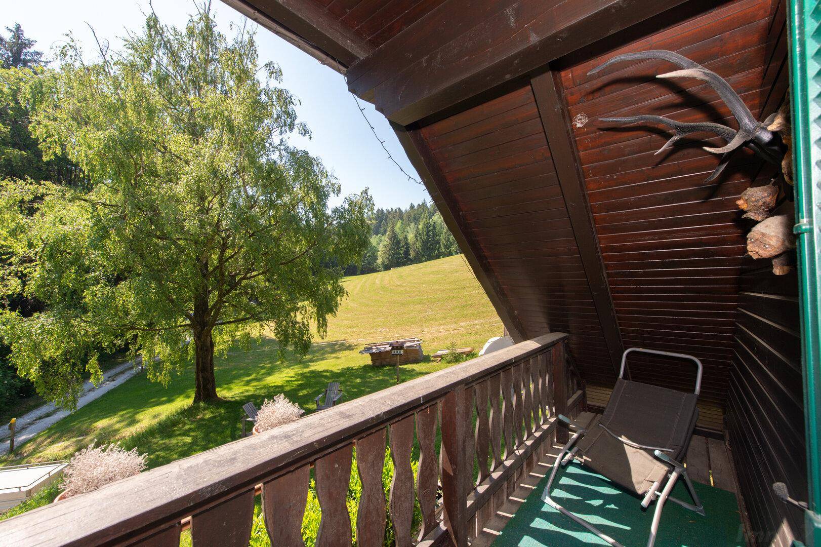 Kleiner Balkon mit Blick auf die grüne Landschaft und alte Bäume.