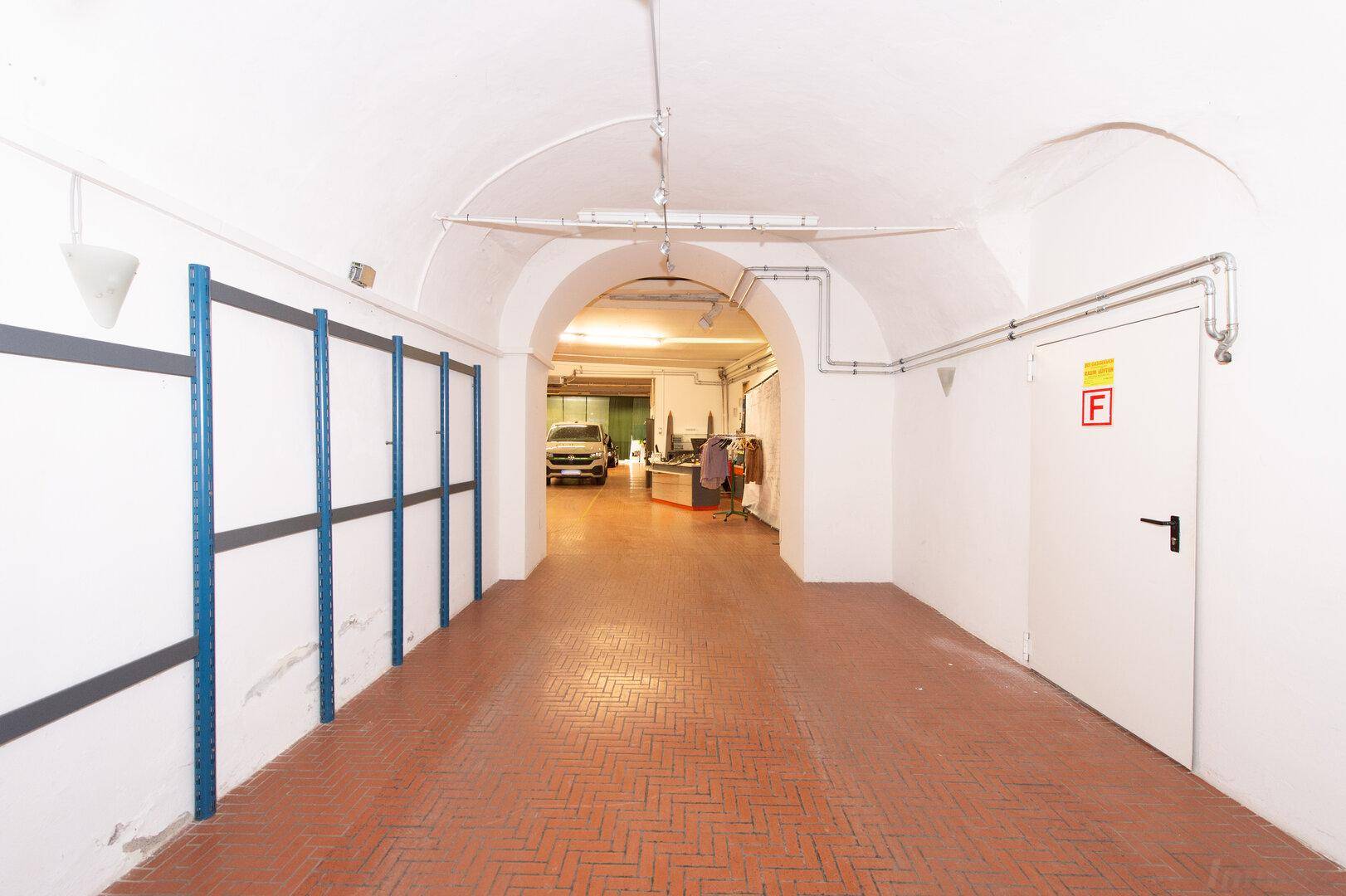 Langer Gang in einer Tiefgarage mit gewölbter Decke und Zugang zu weiteren Bereichen.