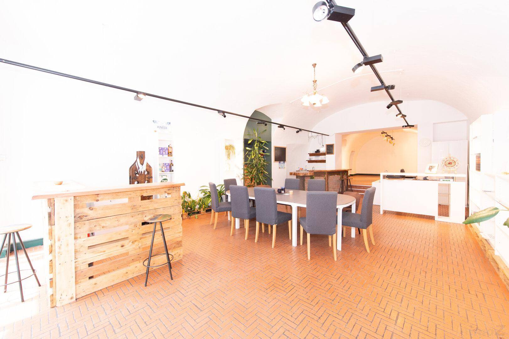 Großer Raum mit Esstisch, Stühlen und einer Holzbar, ideal für Veranstaltungen oder Besprechungen.